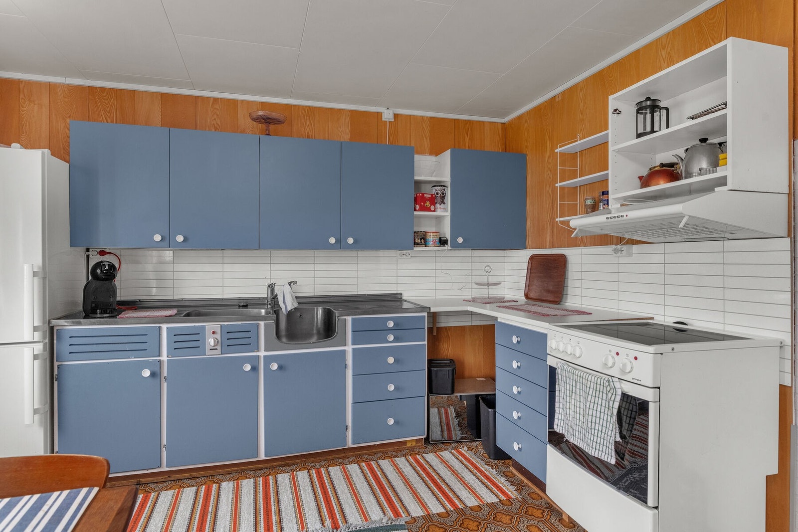 Eldre kjøkkeninnredning med skap og benkeplass, samt løse hvitevarer Galleribilde