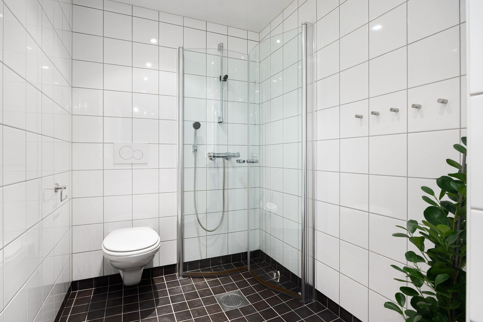 Videre har badet vegghengt toalett med innebygd sisterne samt dusjsone med innfelte dusjdører i herdet glass. Galleribilde