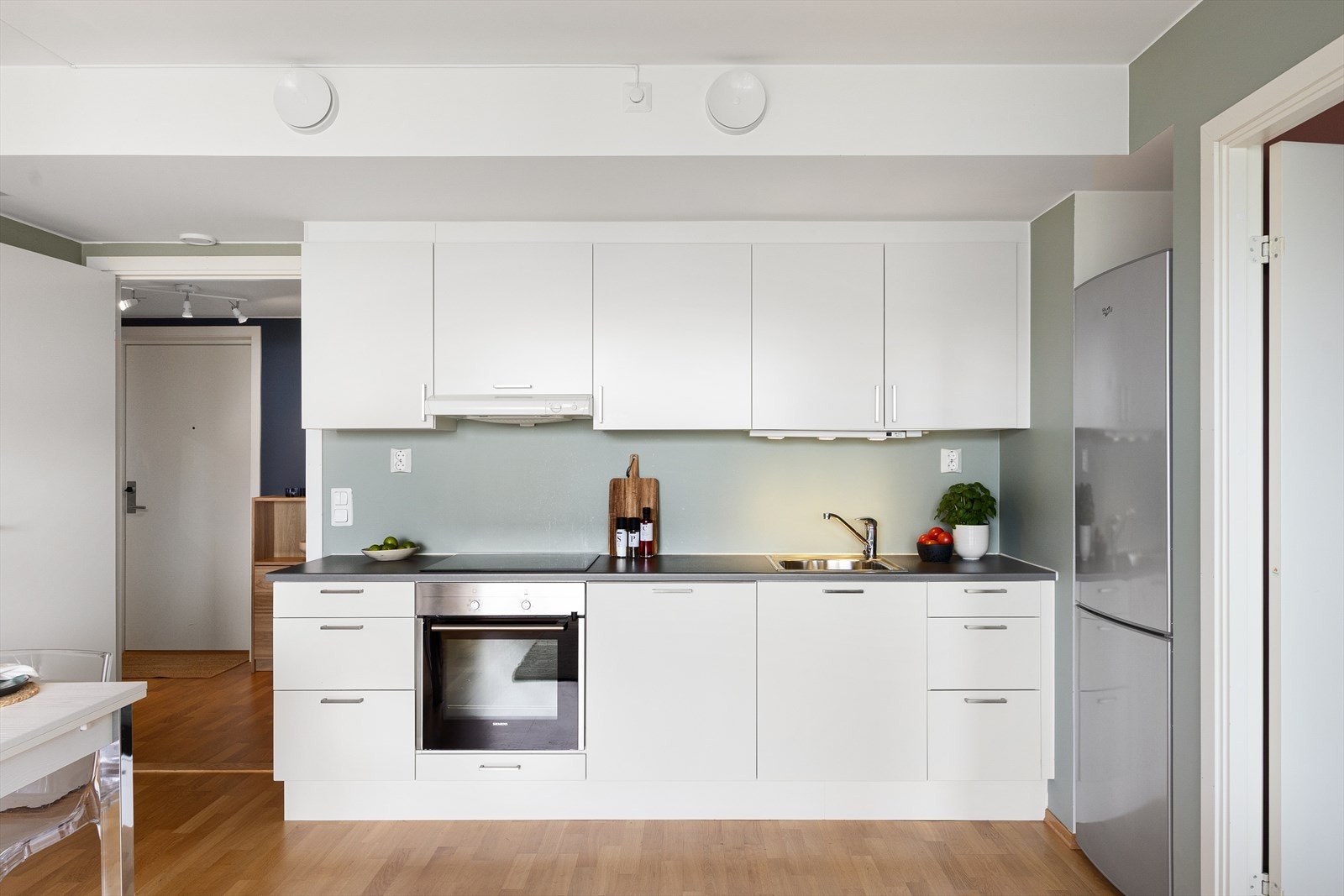 Innredningen har hvite, glatte fronter, laminat benkeplate og nedfelt oppvaskkum med ettgreps svingbart blandebatteri. Kjøkkenet er utstyrt med både over- og underskap, samt belysning under overskap. Galleribilde