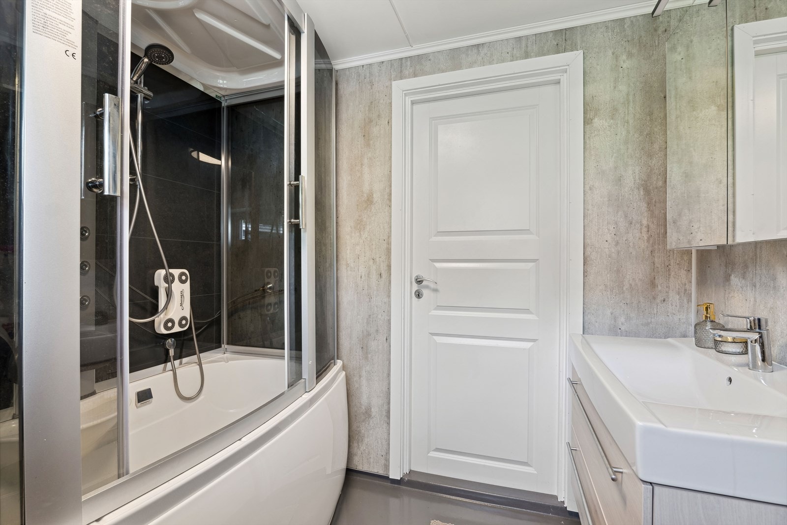 Badet er utstyrt med dusjkabinett med badekar, baderomsinnredning med nedfelt servant og speilskap, samt opplegg for vaskemaskin. Galleribilde
