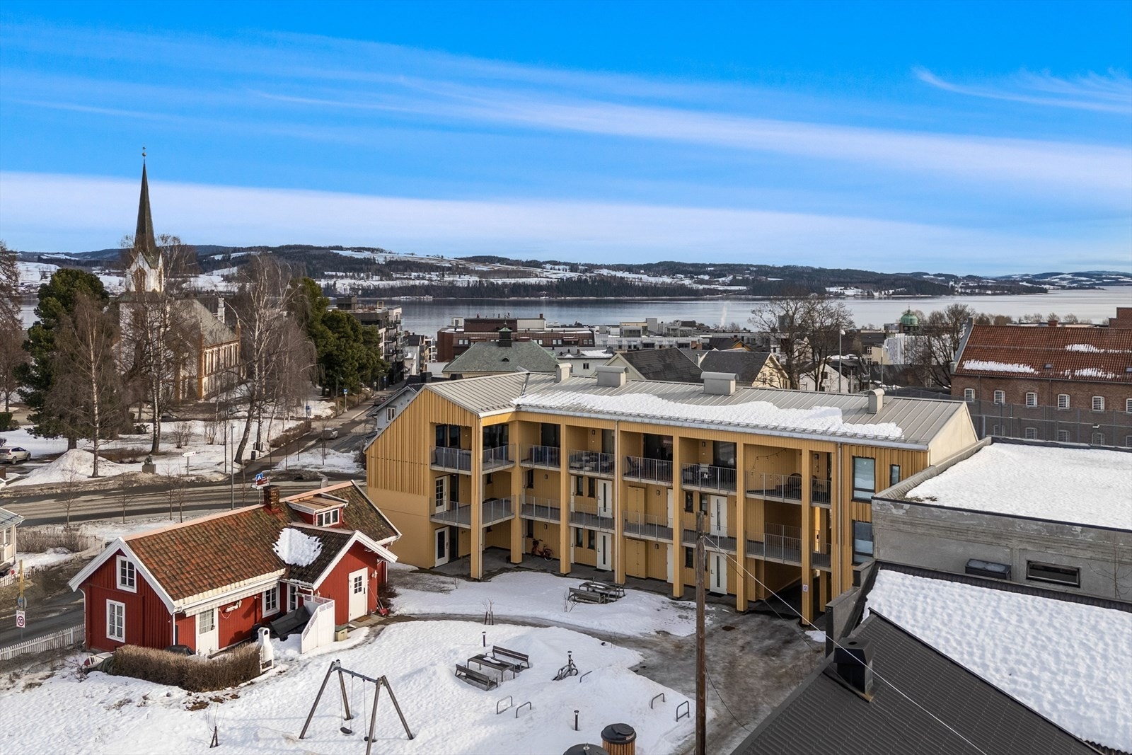 Dronefoto av fasade og bakgård med tilhørende fellesareal og lekeplass Galleribilde