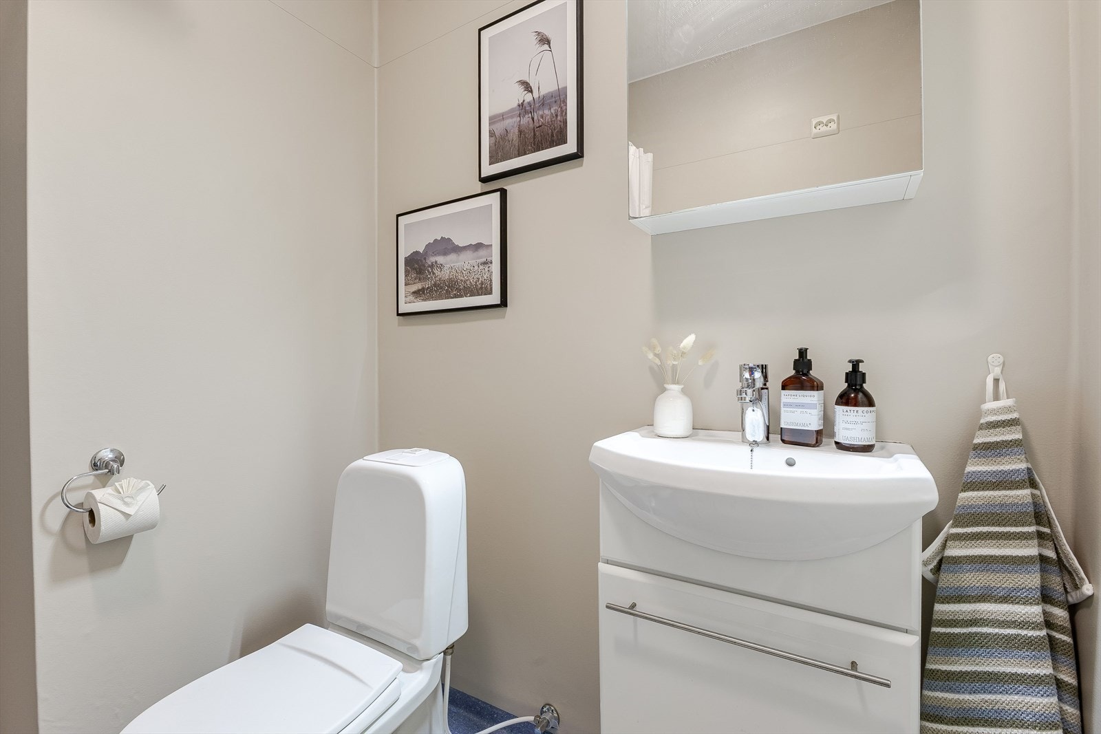 Badet er lyst og stilrent med hvite baderomsmøbler og speilskap over servant. Galleribilde