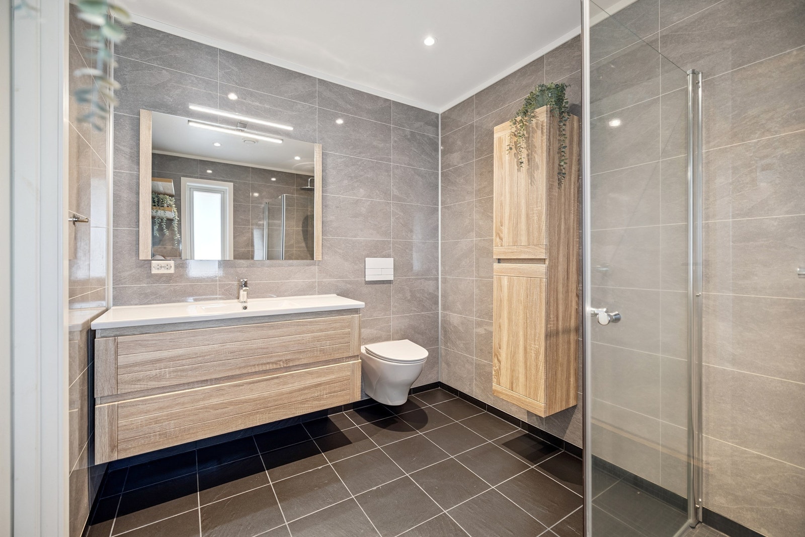 Baderomsinnredning med heldekkende servant, speil med lys og god skapplass. Galleribilde