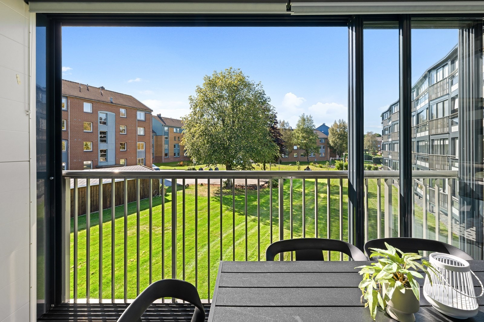 Utsikt fra den innglassede balkongen mot grønt og trivelig gårdsrom Galleribilde