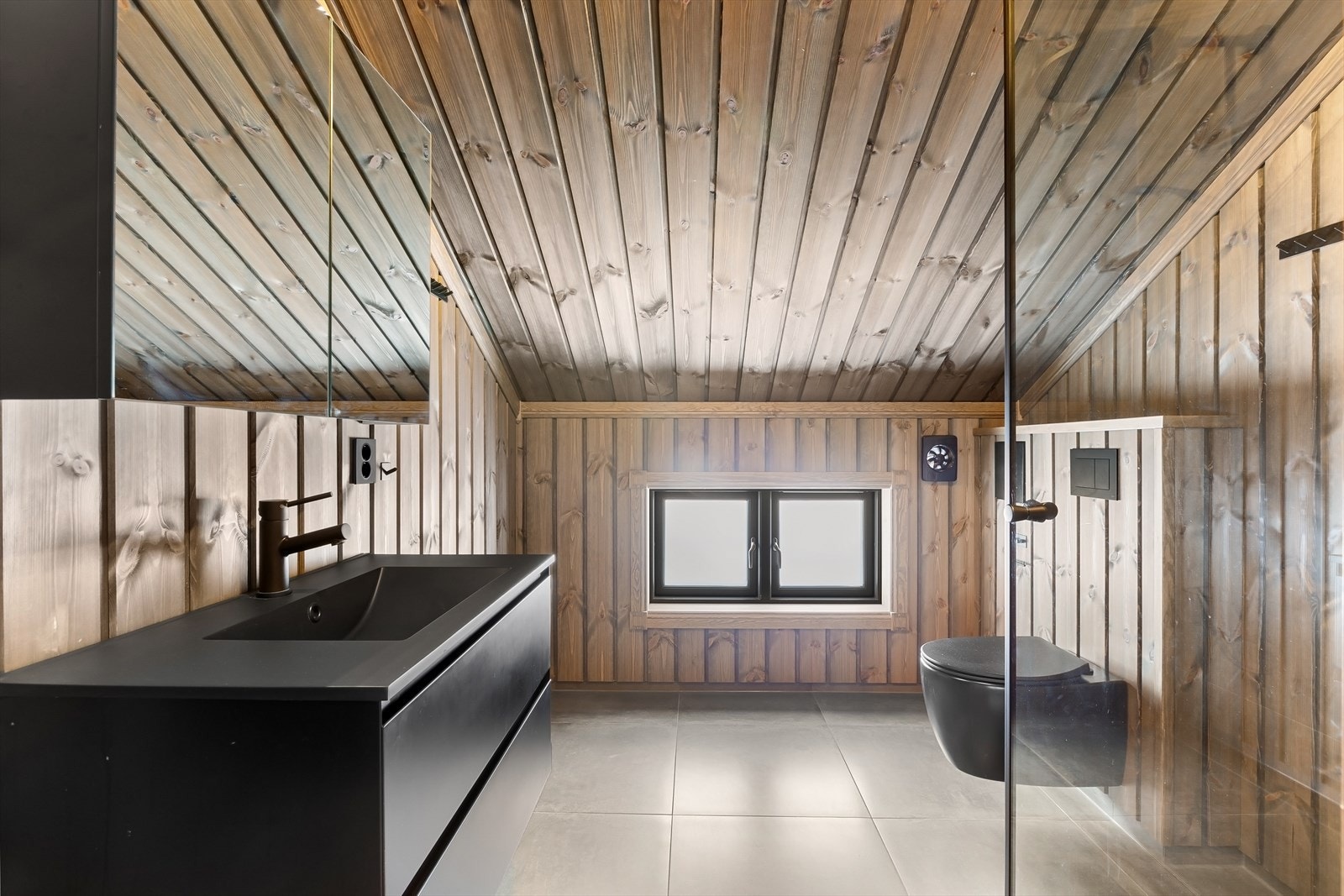 Lyst og moderne bad i loftsetasjen med skråtak og gjennomført materialbruk Galleribilde