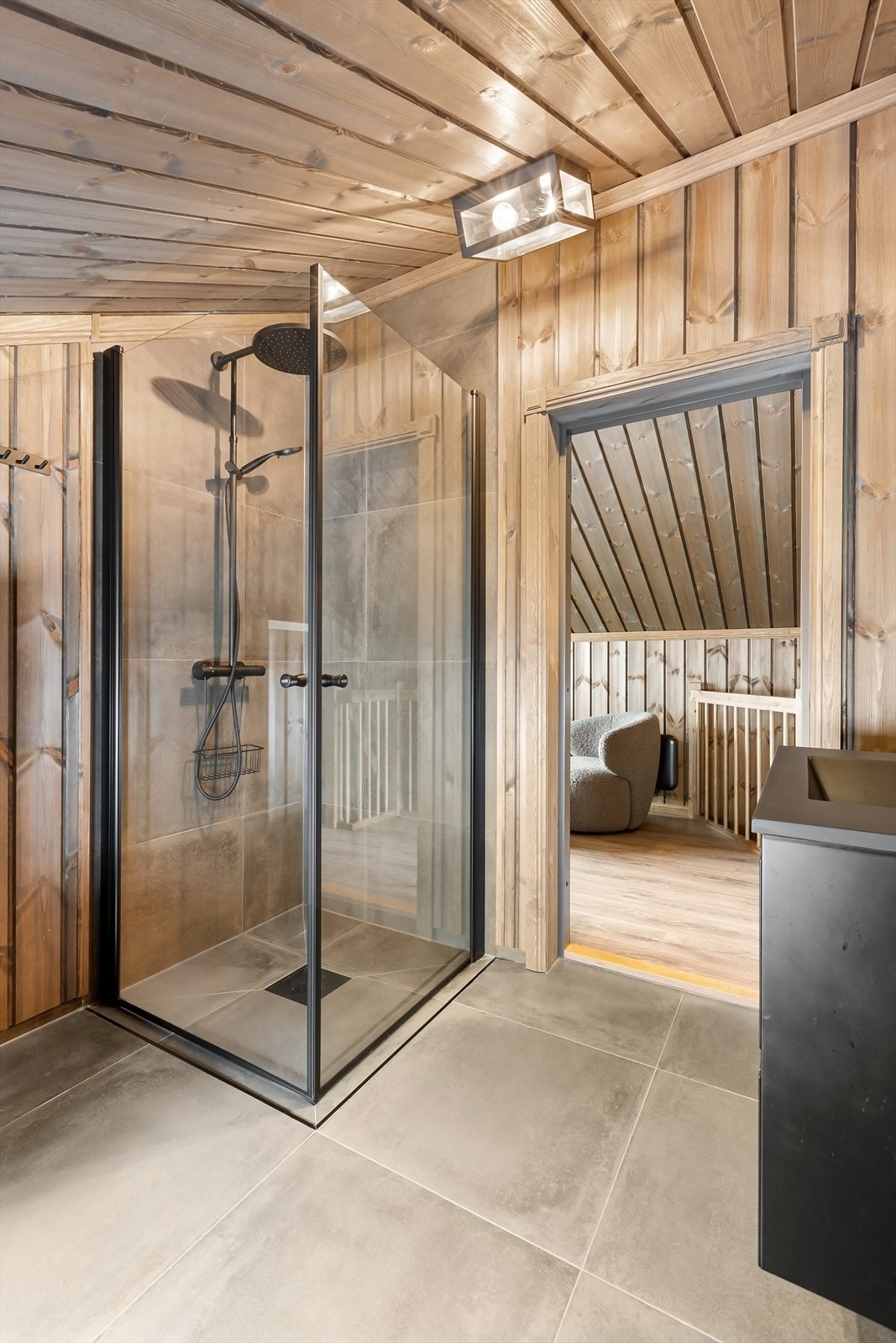 Store, mørke fliser på gulv og i dusjsonen står i kontrast til den lune trefinishen på vegger og tak Galleribilde