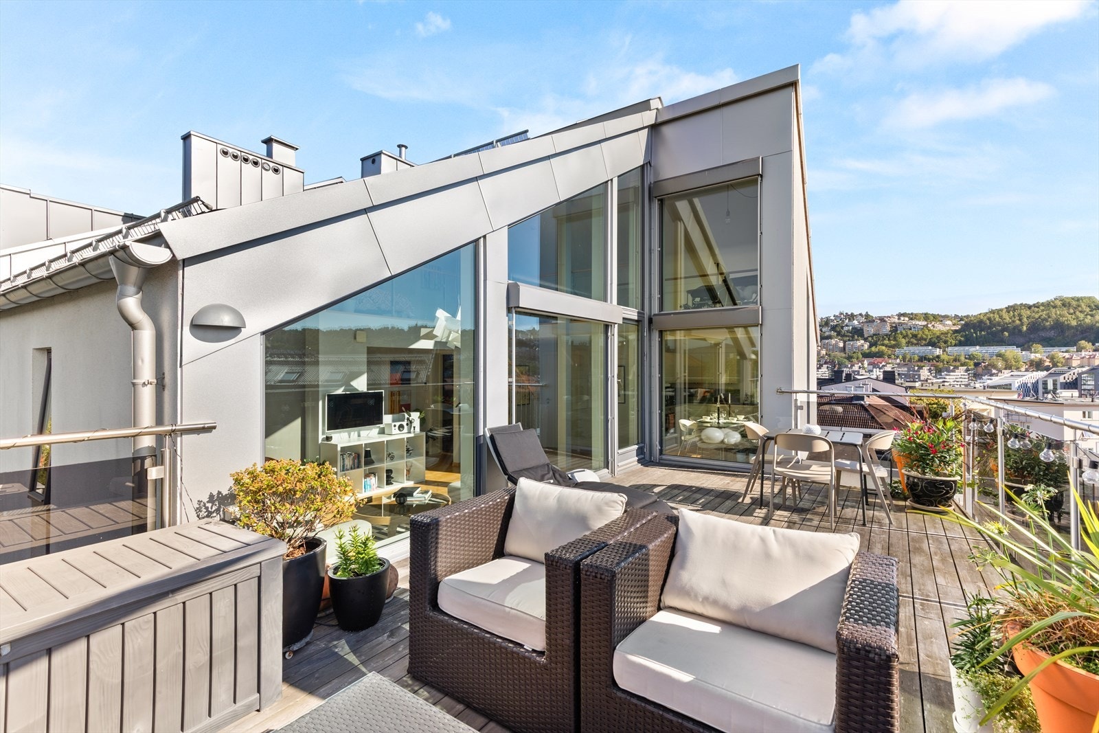 Terrassen er romslig, med plass til ulike sittegrupper, planter, grill og parasoll Galleribilde