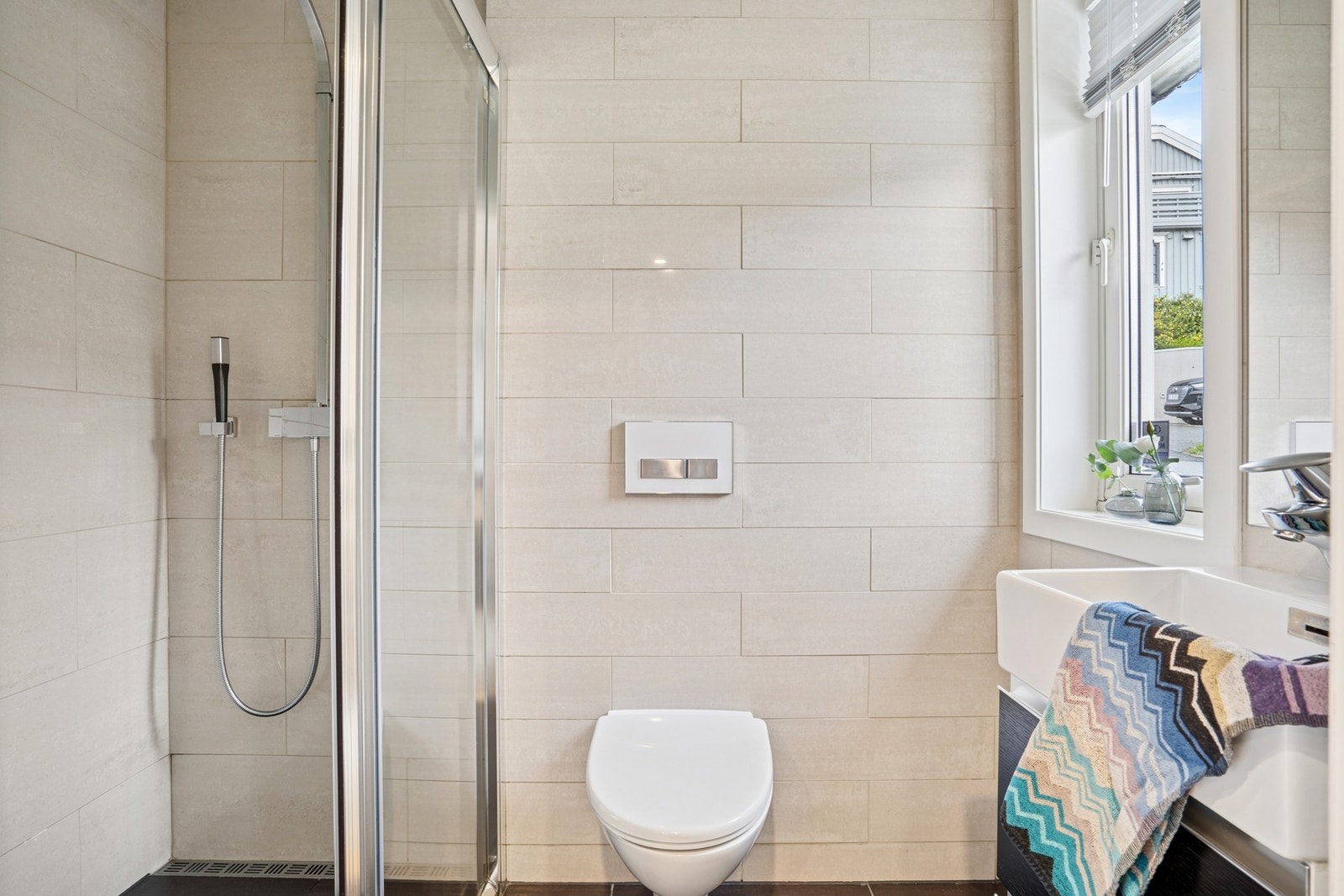 Det andre baderommet er med flis i behagelige duse farger, varmekabler i gulv, vegghengt wc, spadusj og servant med underskap. Downlights i tak gir god beslysning. Badet ble oppgradert i 2016 og fremstår som både moderne og funksjonelt. Galleribilde