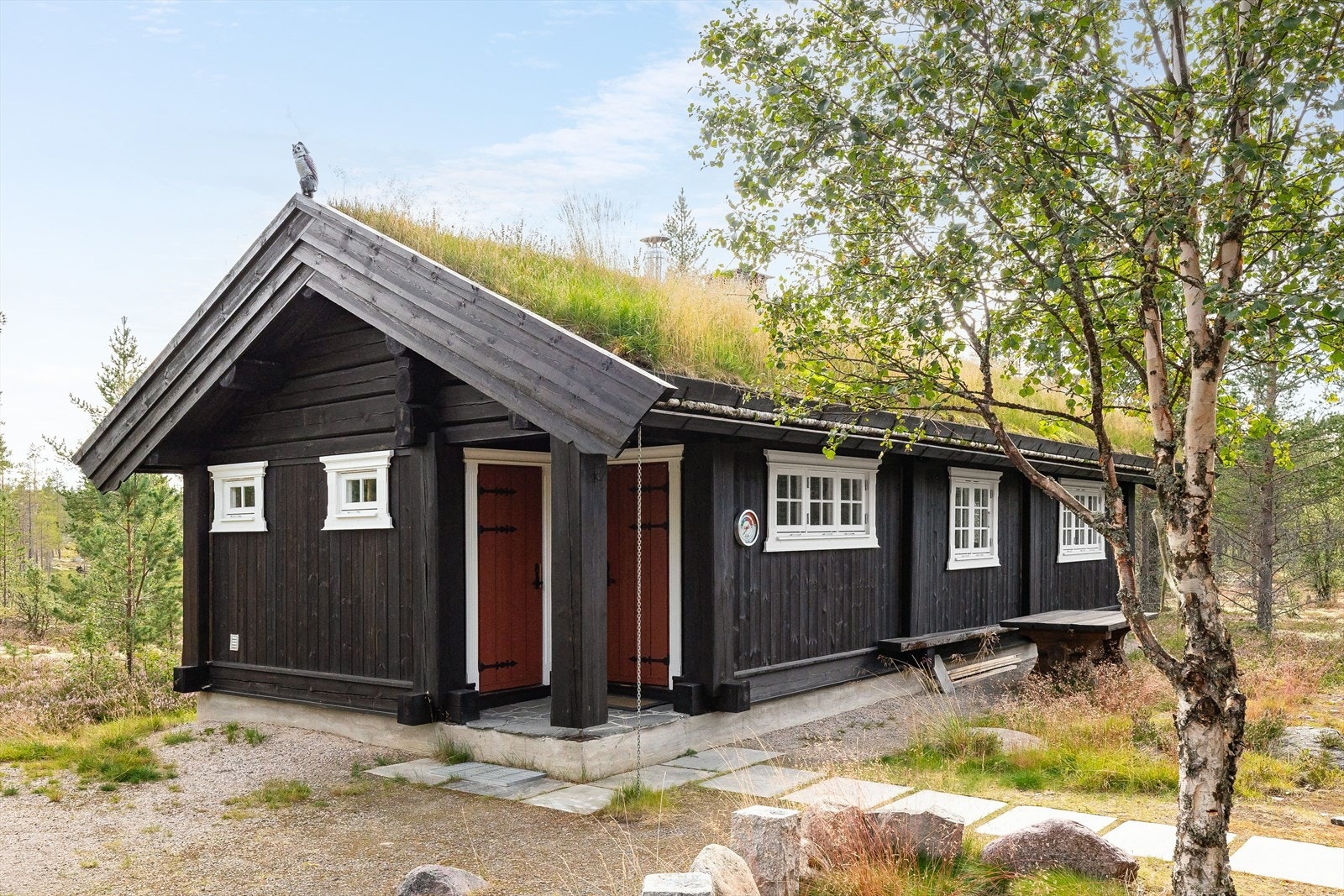 Flott hytte fra 2009 med yttervegger av stavlaft utvendig kledd med stående trekledning og tak tekket med torv. Galleribilde