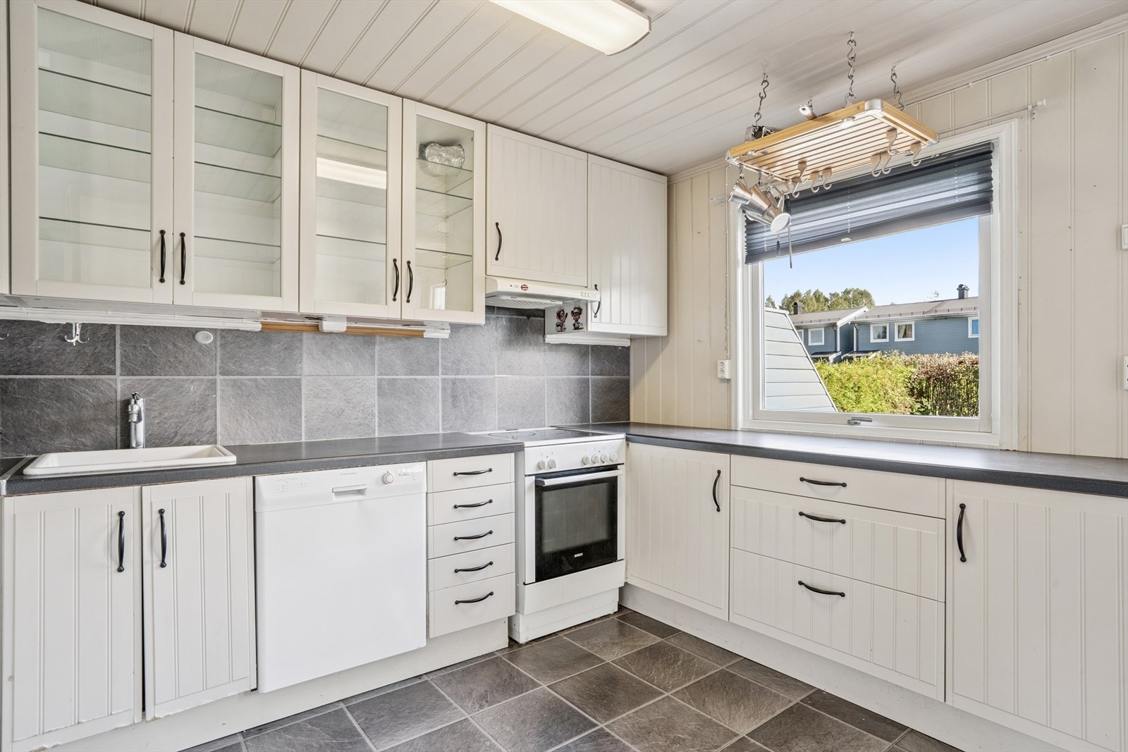 Kjøkkeninnredningen har stilrene vitrinedører og nedfelt porselenskum. Galleribilde