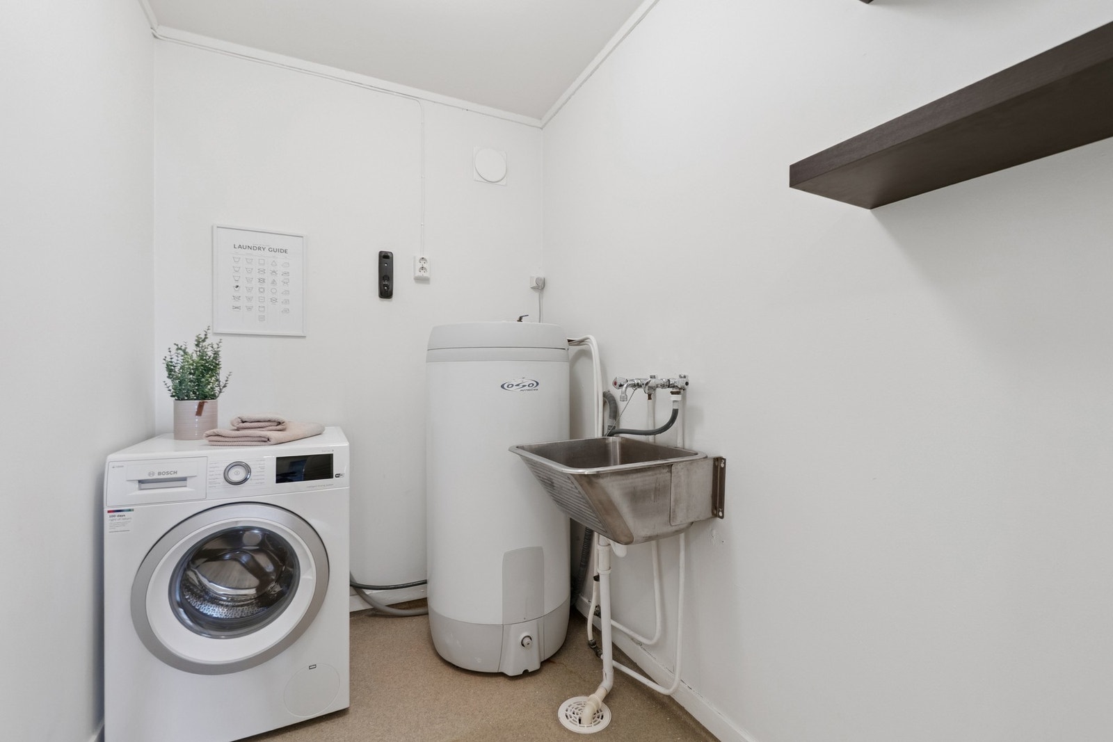 Vegg-i-vegg med badet finner du boligens vaskerom. Galleribilde