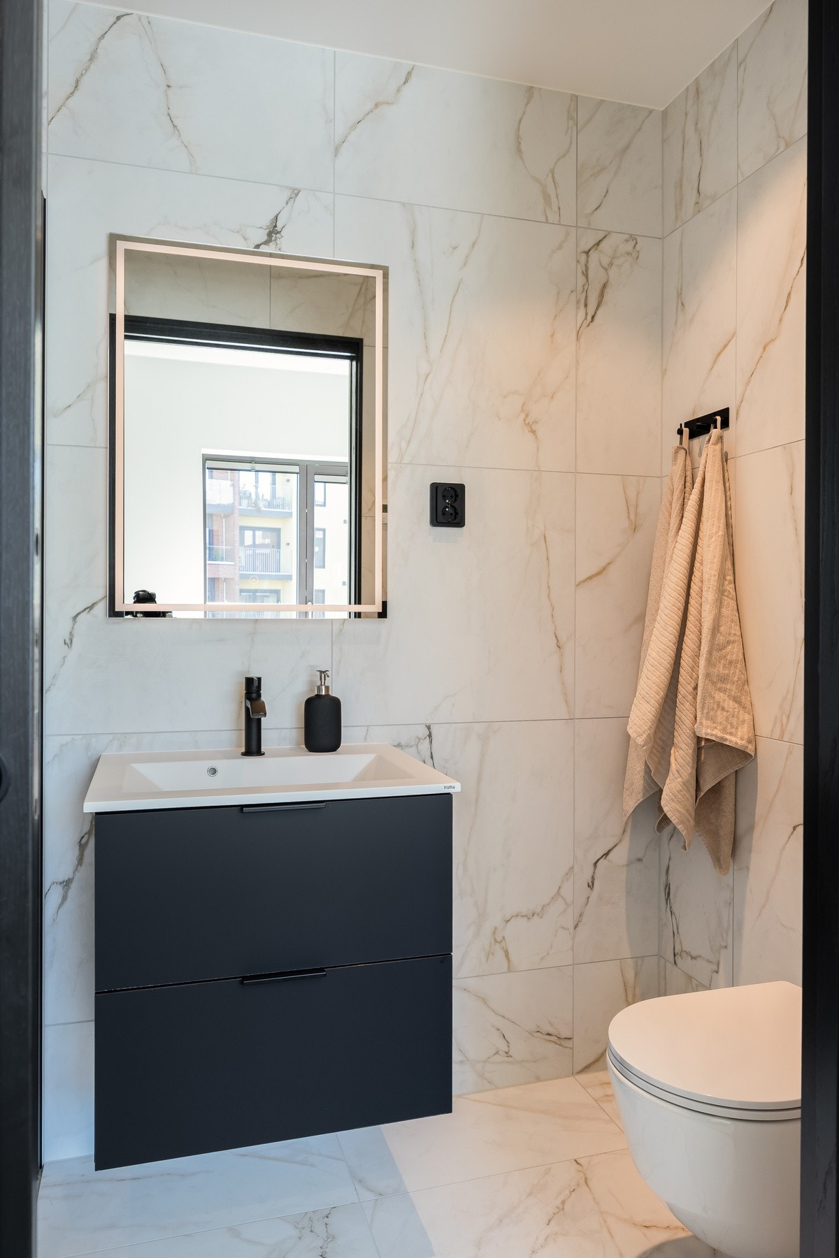 Badet innehar dusjsone med innebygd armatur, servant med underskuffer og vegghengt toalett. Galleribilde