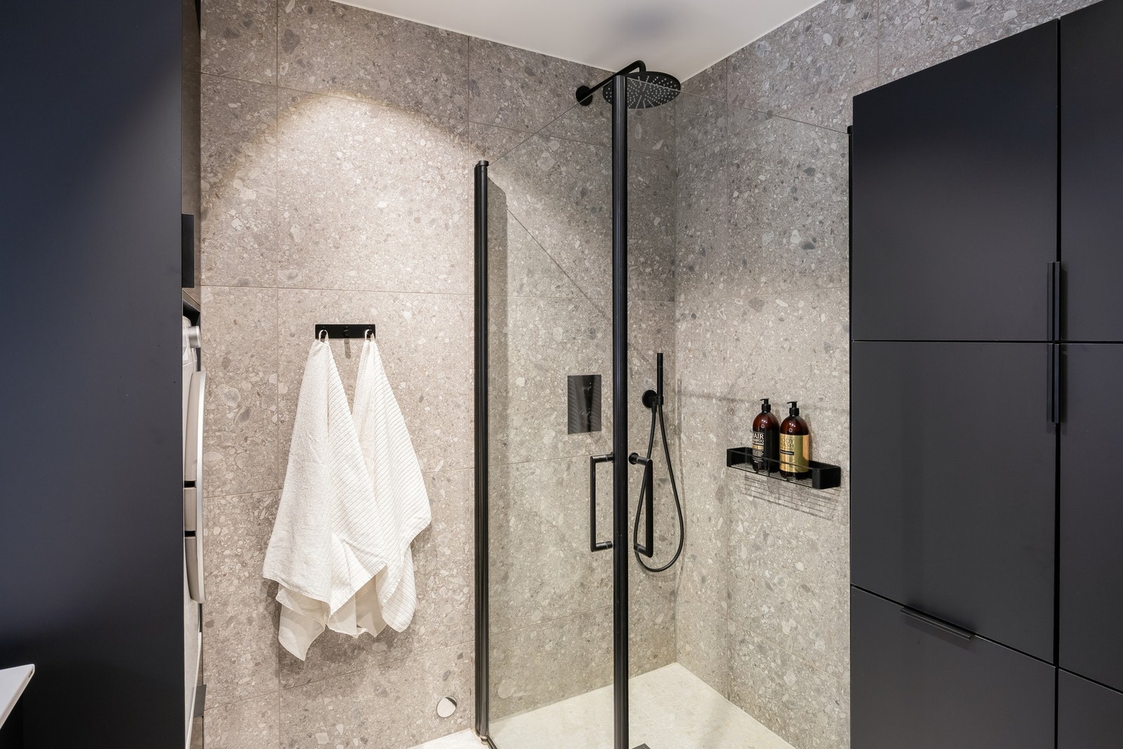 Hovedbadet er utstyrt med dusjnisje med lekre sorte detaljer, baderomsmøbel fra JKE, egen nisje og innredning for vaskemaskin, og vegghengt toalett. Galleribilde