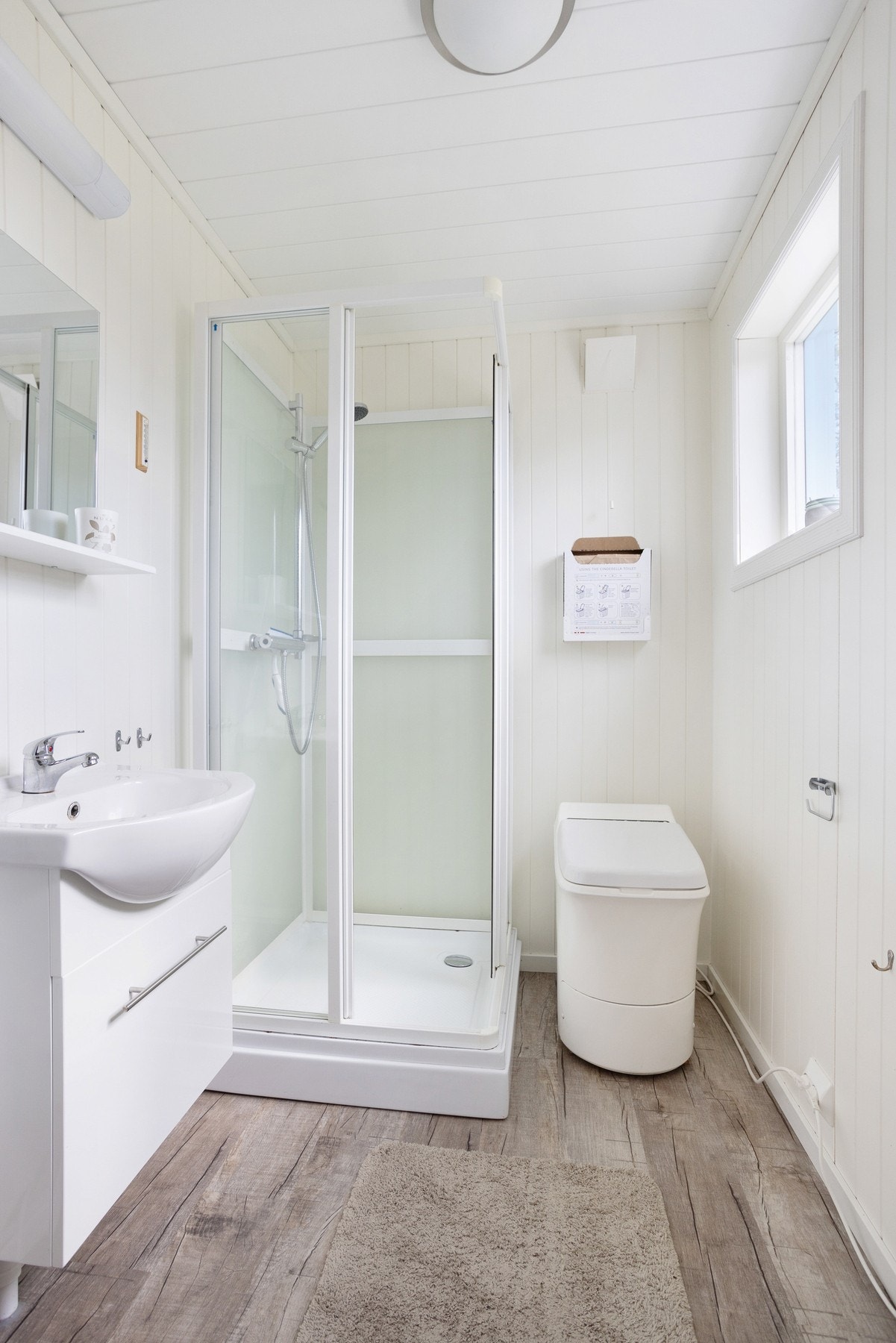 Baderom med Cinderella forbrenningstoalett, dusjkabinett og servant Galleribilde