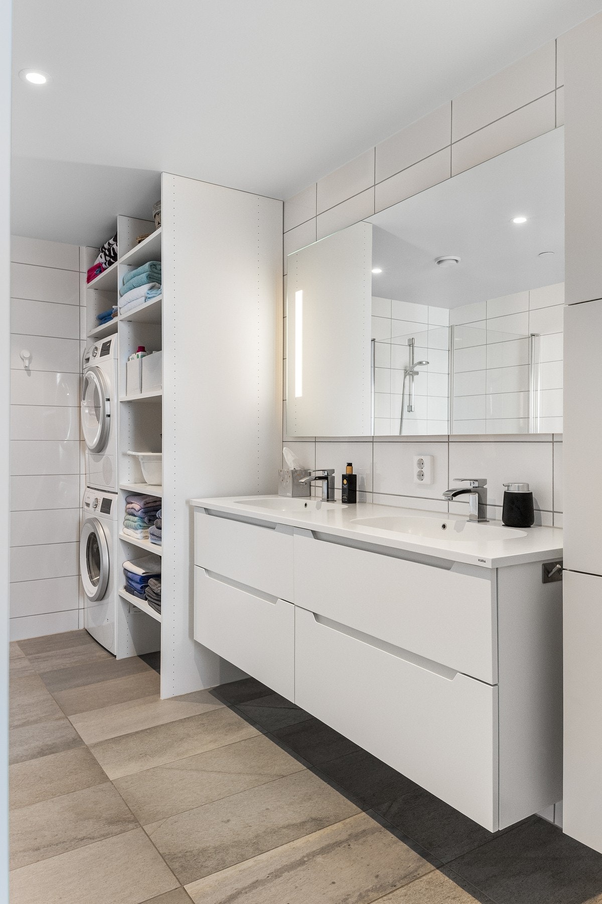 Badet har blant annet hvit skuffeinnredning med heldekkende dobbelservant, og over er det speil med integrert belysning.