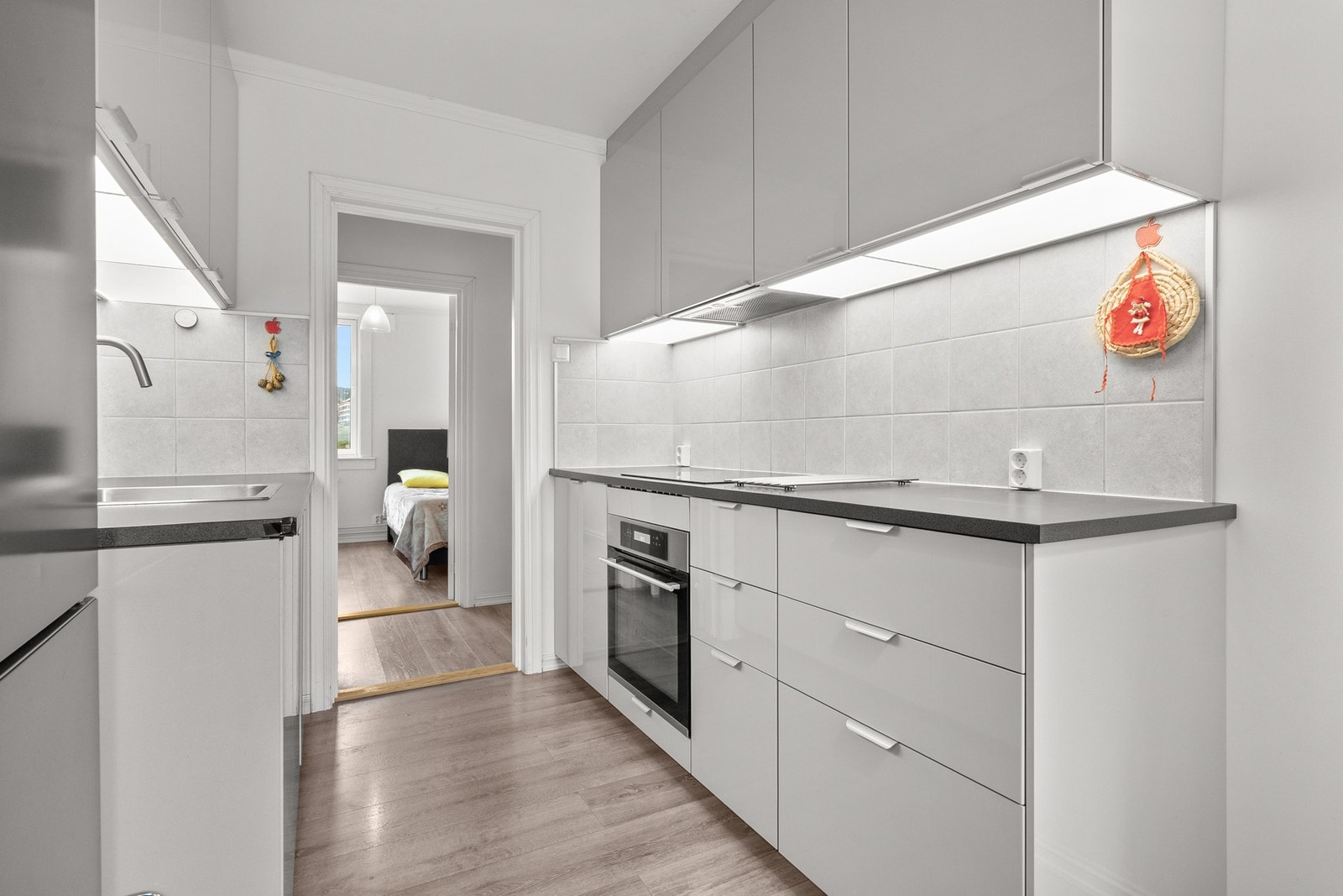 Innredningen har lyse grå fronter og en benkeplate med matchende grå fliser over. Galleribilde