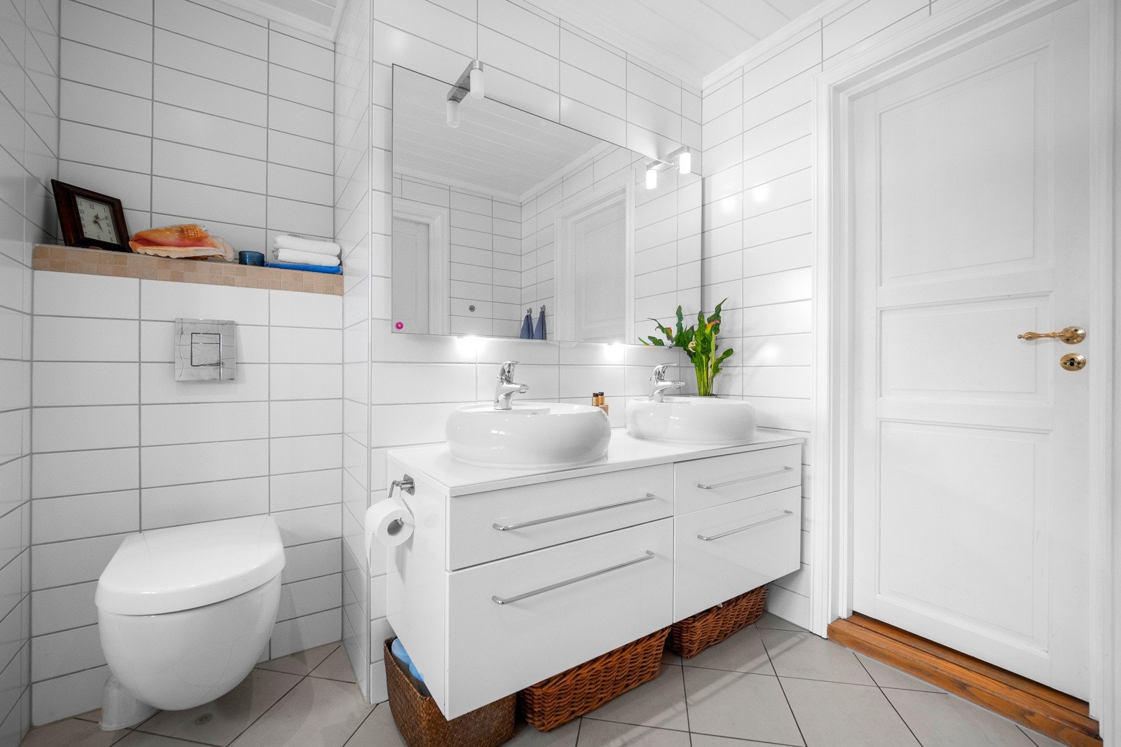 Badet er innredet med servantskap med dobbel servant, dusj, badekar og toalett Galleribilde