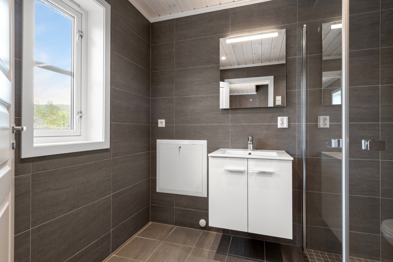 Badet har dusjhjørne med innfellbare dusjvegger i klart glass. Galleribilde