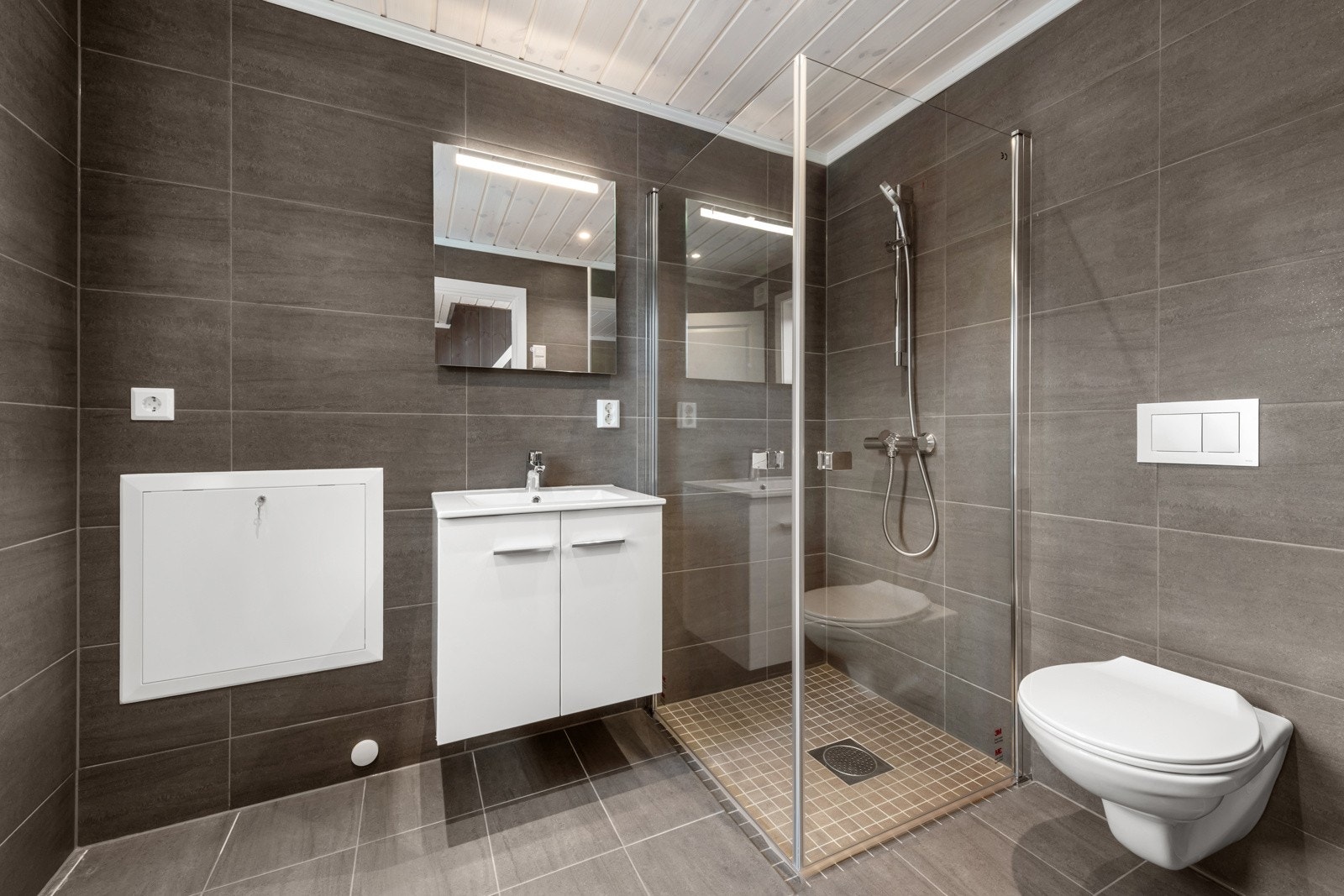 Fritidsboligen har to bad, og begge er lekkert innredet med grå fliser på gulv og vegger. Galleribilde