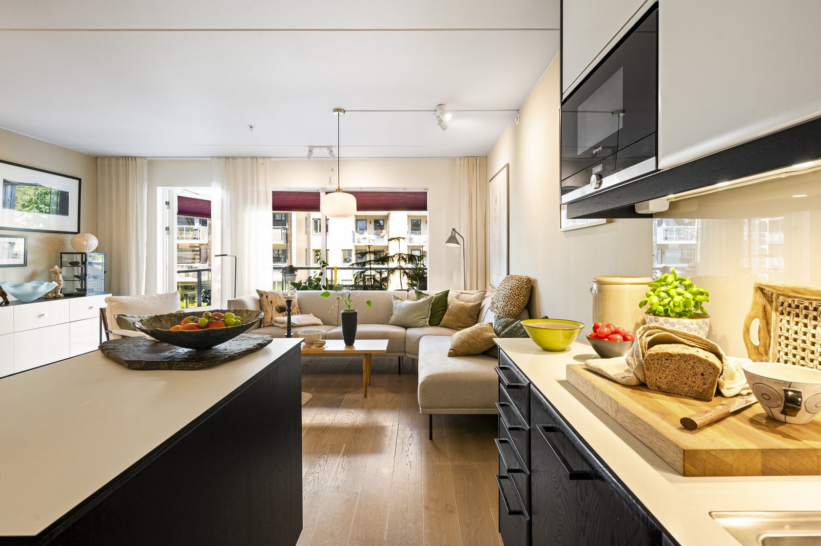 Store vindusflater som slipper inn rikelig med naturlig lys med utsikt over rolig gårdsrom skaper en god atmosfære i stuen. Galleribilde