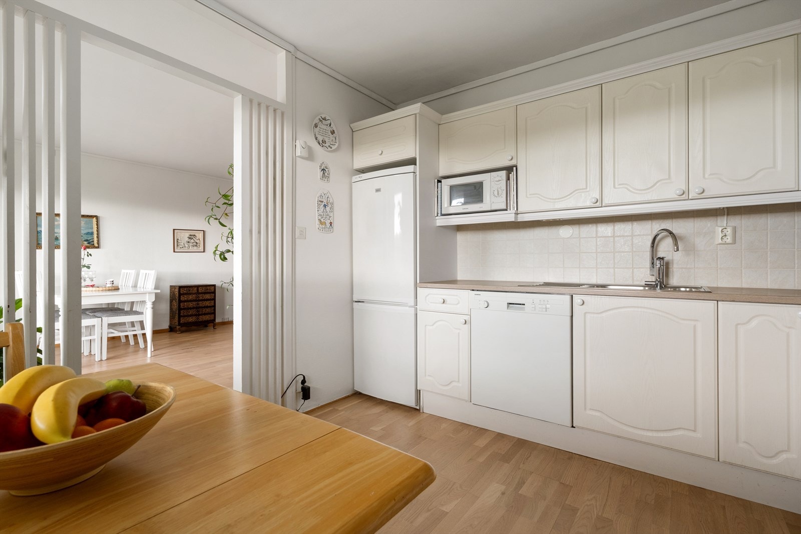 Romslig kjøkken med hvite profilerte fronter. Galleribilde