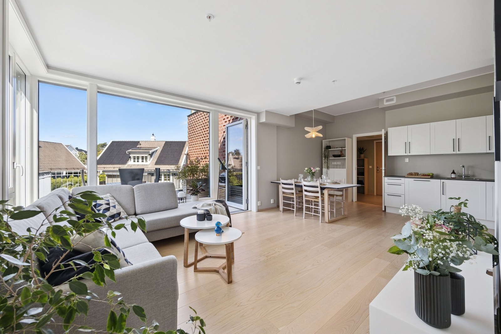 Store vindusflater slipper inn mye naturlig lys og skaper en luftig atmosfære i boligens oppholdssone. Galleribilde