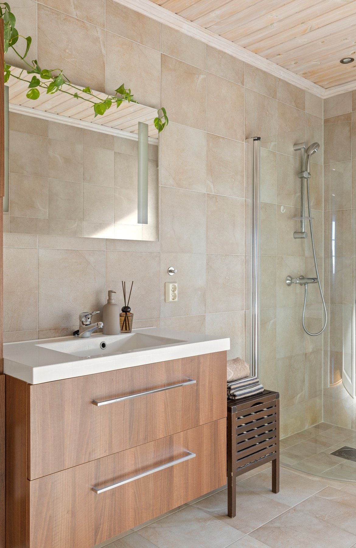 Badet fremstår som velholdt og pent, med downlights i himlingen, sandfargede fliser på veggene og matchende fliser på gulv med vannbåren gulvvarme. Galleribilde