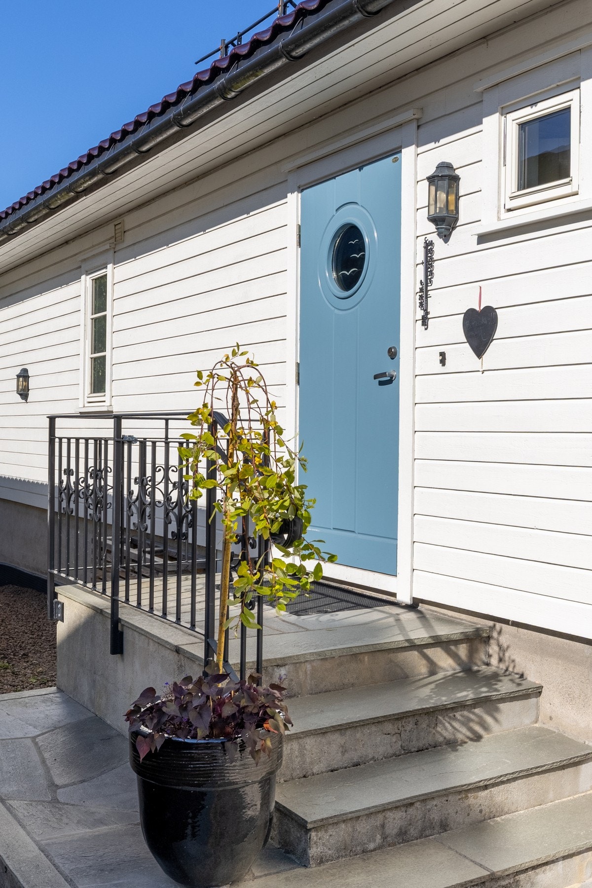 Eneboligen har et pent inngangsparti med steinbelagt adkomst, skiferlagt trapp og veggmontert utebelysning. Galleribilde