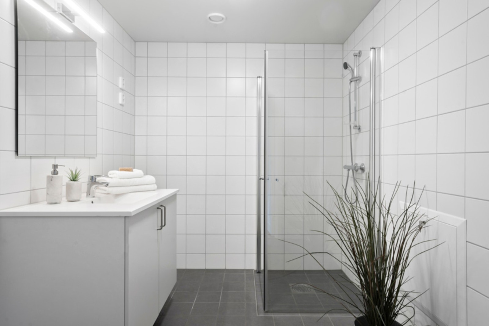 Innbydende baderom med dusjhjørne og opplegg for vaskemaskin Galleribilde