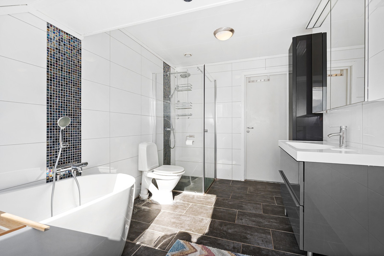 Innholdsrikt bad med både badekar og dusj. Godt med oppbevaring i skuffeseksjon og høyskap. Galleribilde