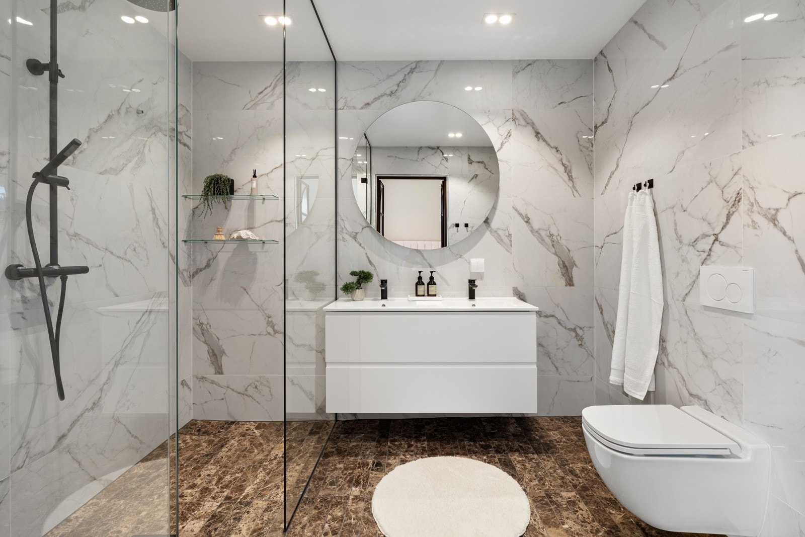 Det tilknyttede badet holder en gjennomgående moderne standard, med fliser på både gulv og vegger, samt et hvitmalt, slett tak som bidrar til et rent og tidløst uttrykk. Galleribilde