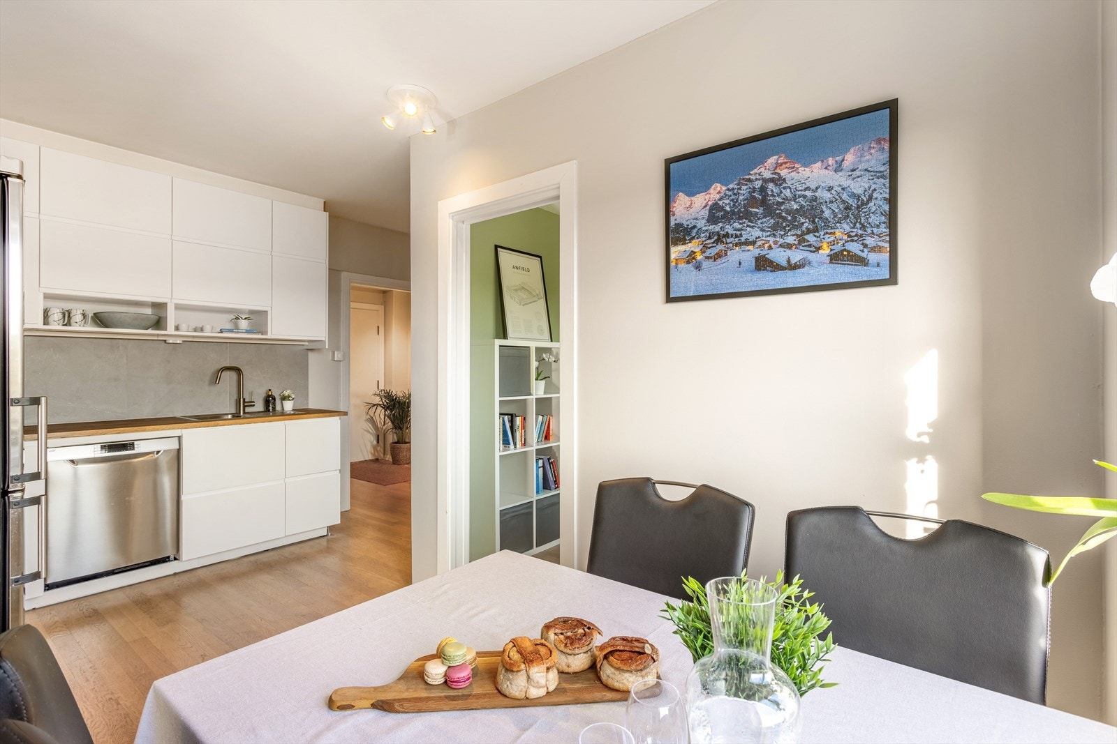 Klassisk kjøkkeninnredning fra 2021 med glatte folierte fronter, benkeplate i tre med nedfelt kum i rustfritt stål, fliser på vegg over benk og ventilator med kullfilter. Galleribilde
