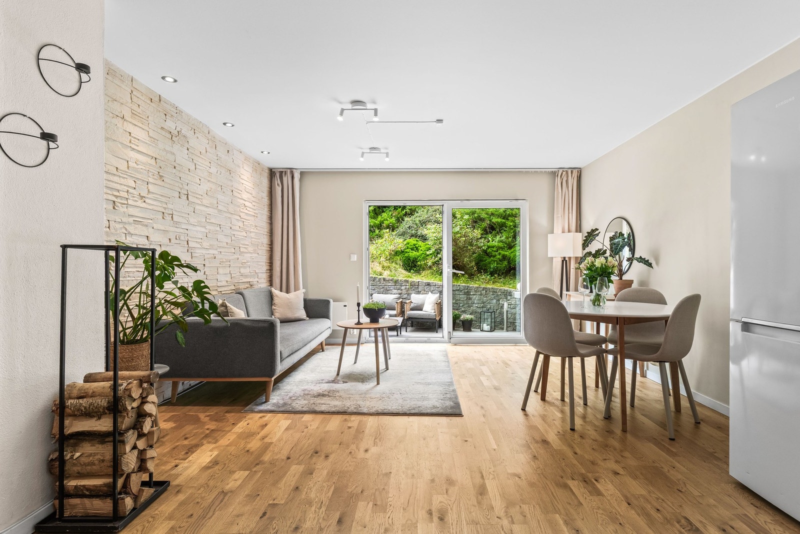 Lys og romslig stue med store vindusflater mot terrassen og grønne omgivelser. Galleribilde