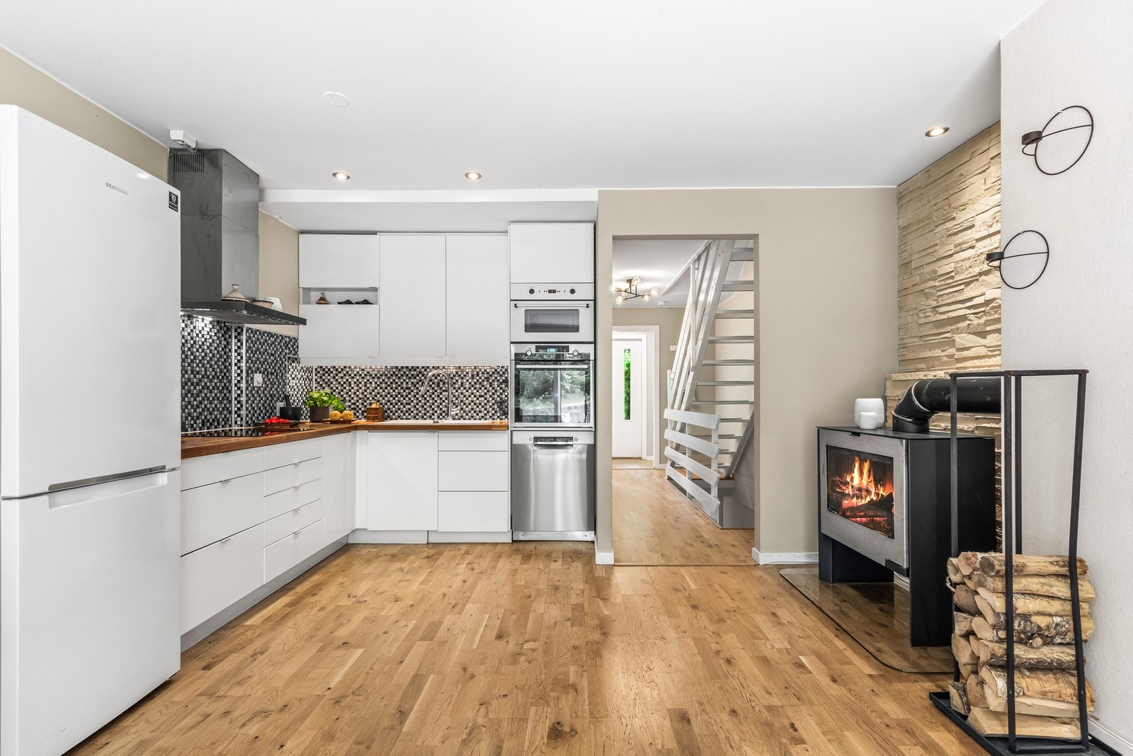 Kjøkkeninnredningen er lys med glatte hvite fronter og pen heltre benkeplate med nedfelt kum i kompositt/plast. Galleribilde