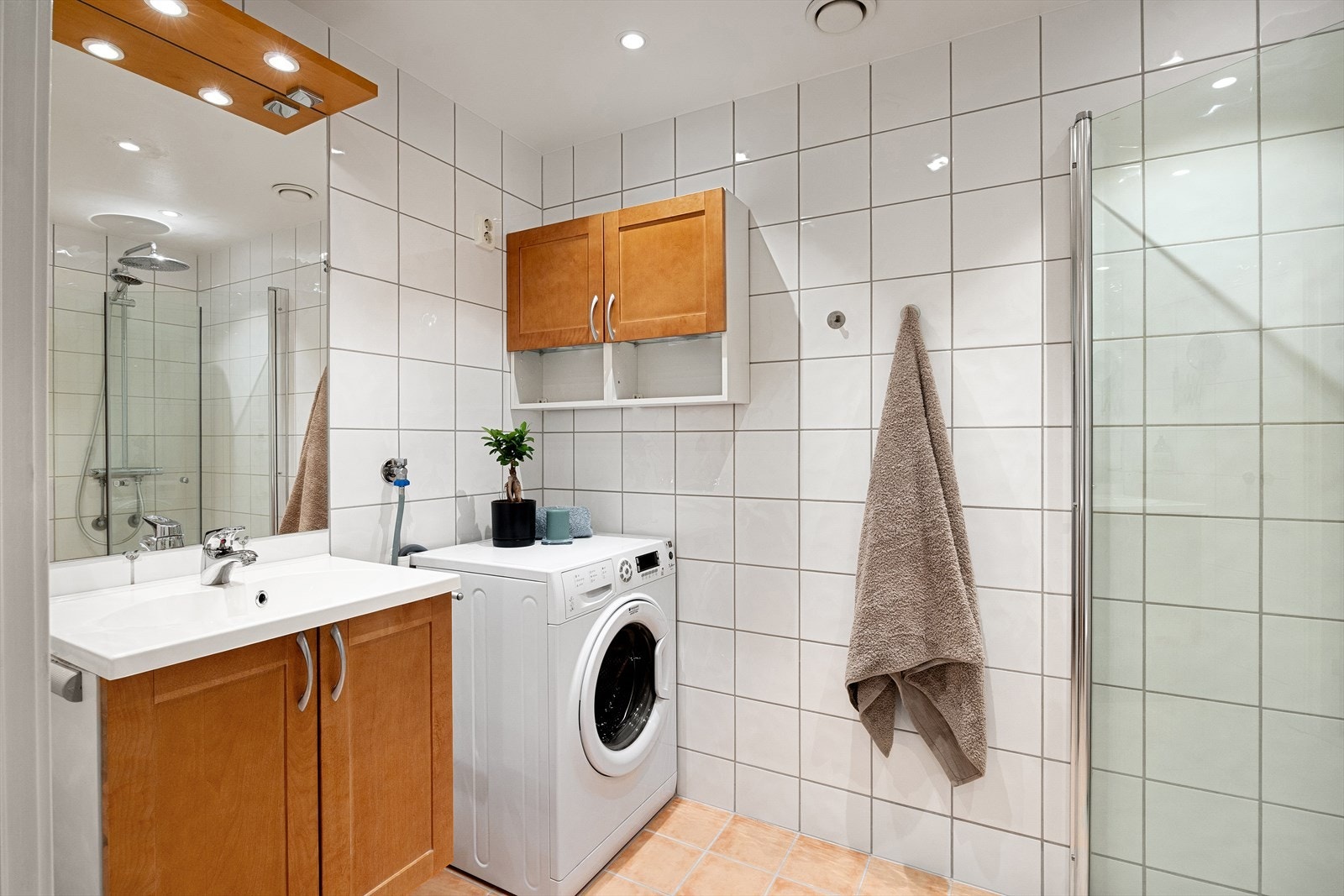 Badet er innredet med servantskap med nedfelt servant, speil med integrert belysning, gulvmontert toalett og dusjsone med innfelte dusjdører i herdet glass. Galleribilde