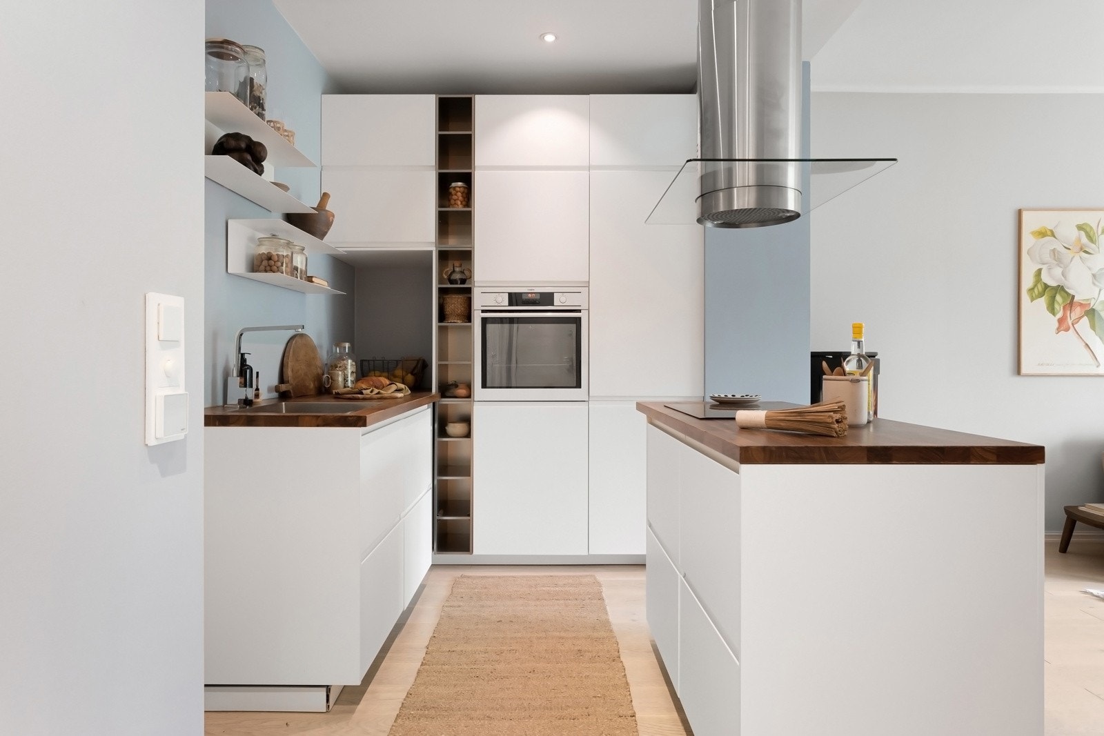 Planløsningen i leiligheten ble endret i 2018/2019 og kjøkkenet ble etablert i åpen løsning til stuen. Innredningen er plassert i en praktisk L-form, innerst i rommet, og har god arbeidsflyt langs stilige benkeplater i Merbau. Galleribilde