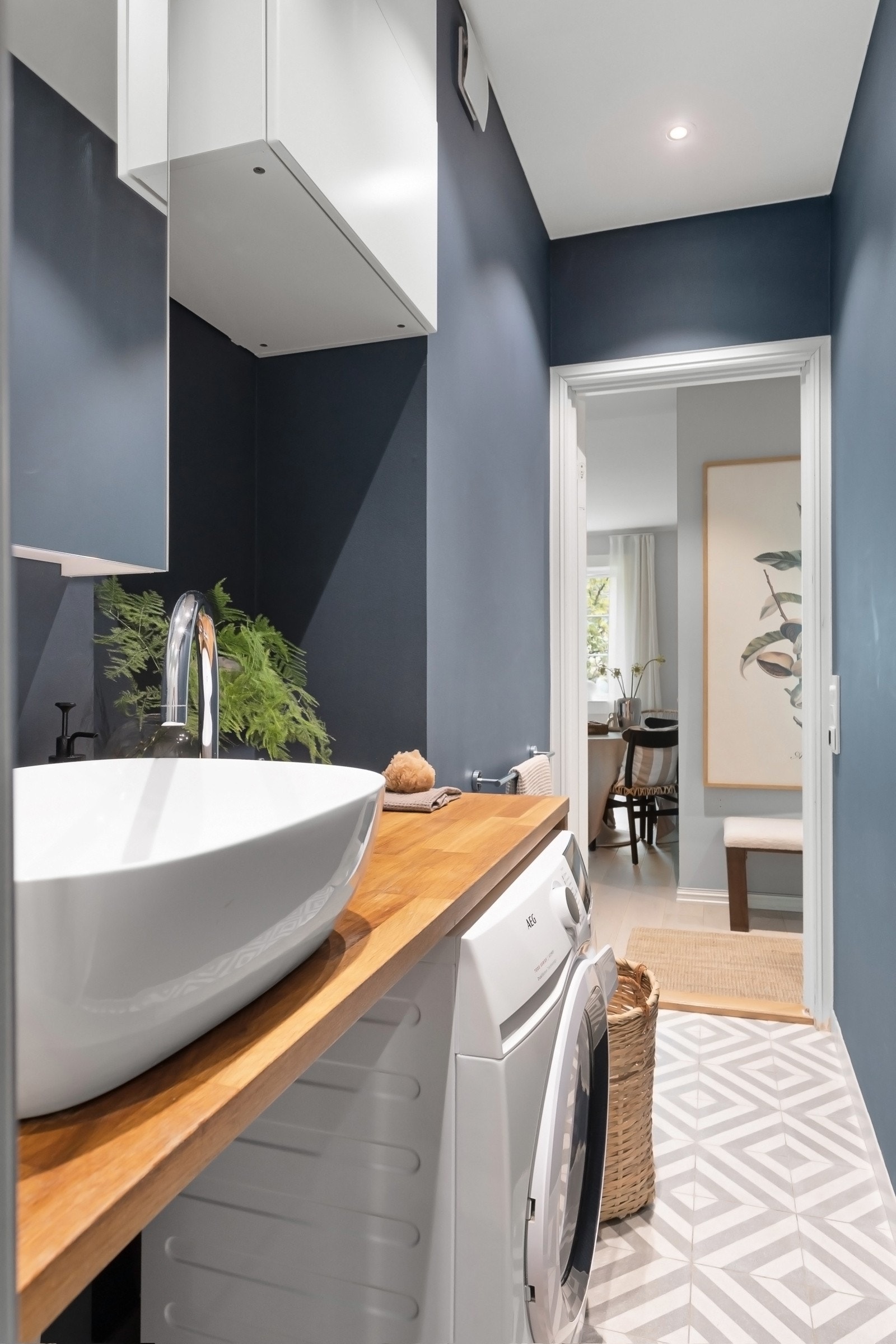 Veggene er malt i en delikat blåtone, og det er varmekabler i gulvet og downlights i himling. Under servantbenken er det nisje til vaskemaskin. Galleribilde