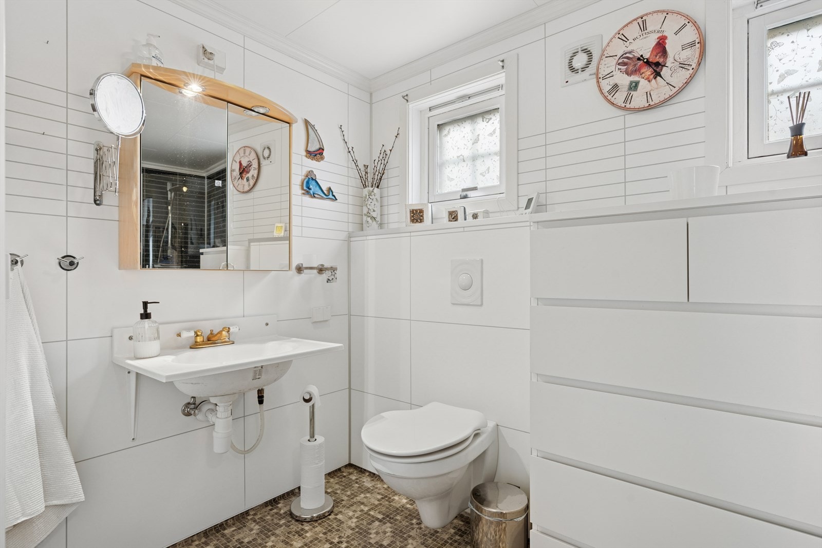 Rommet er innredet med håndvask, vegghengt toalett, dusj og opplegg for vaskemaskin. Det er montert avtrekksvifte i vegg fra våtrom. Galleribilde