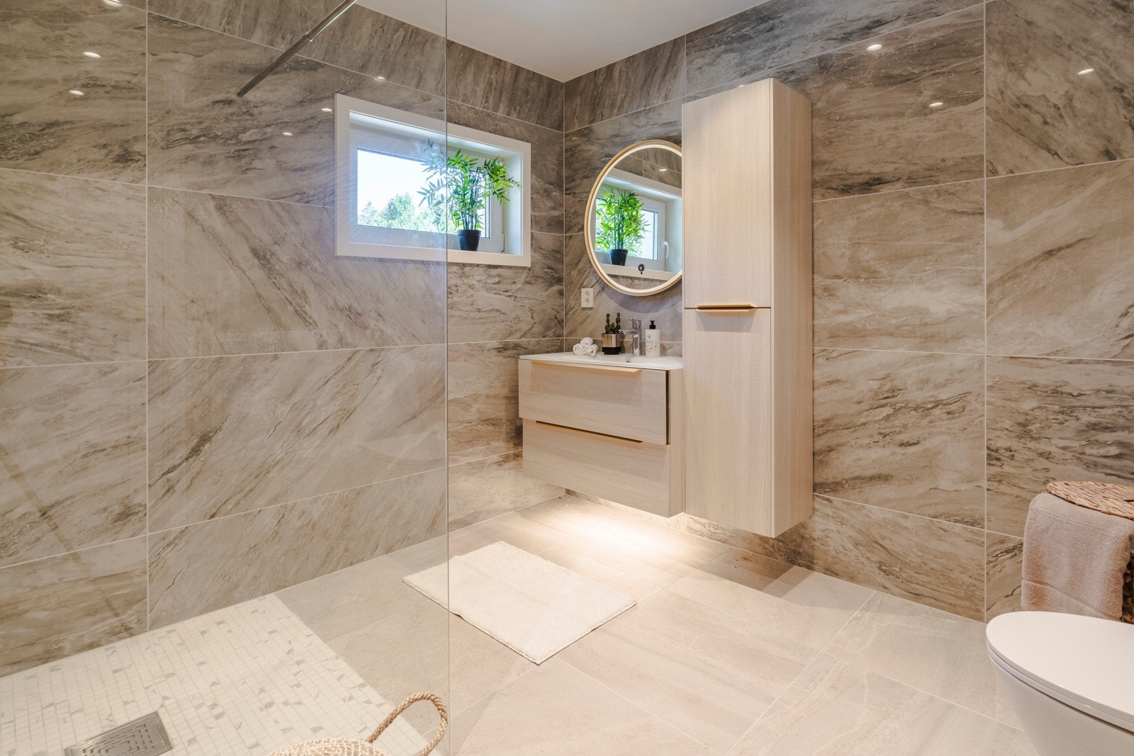Badet i 2. etasje fremstår moderne og stilrent, med flislagt gulv lagt direkte på betong, noe som gir et solid og varig underlag. Galleribilde