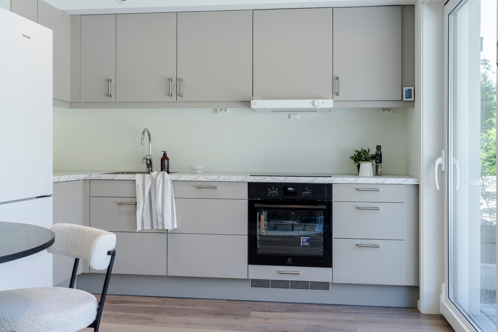 Løsningen er moderne og funksjonell, med integrerte hvitevarer som stekeovn, platetopp og oppvaskmaskin, noe som gir et helhetlig og ryddig uttrykk. Galleribilde