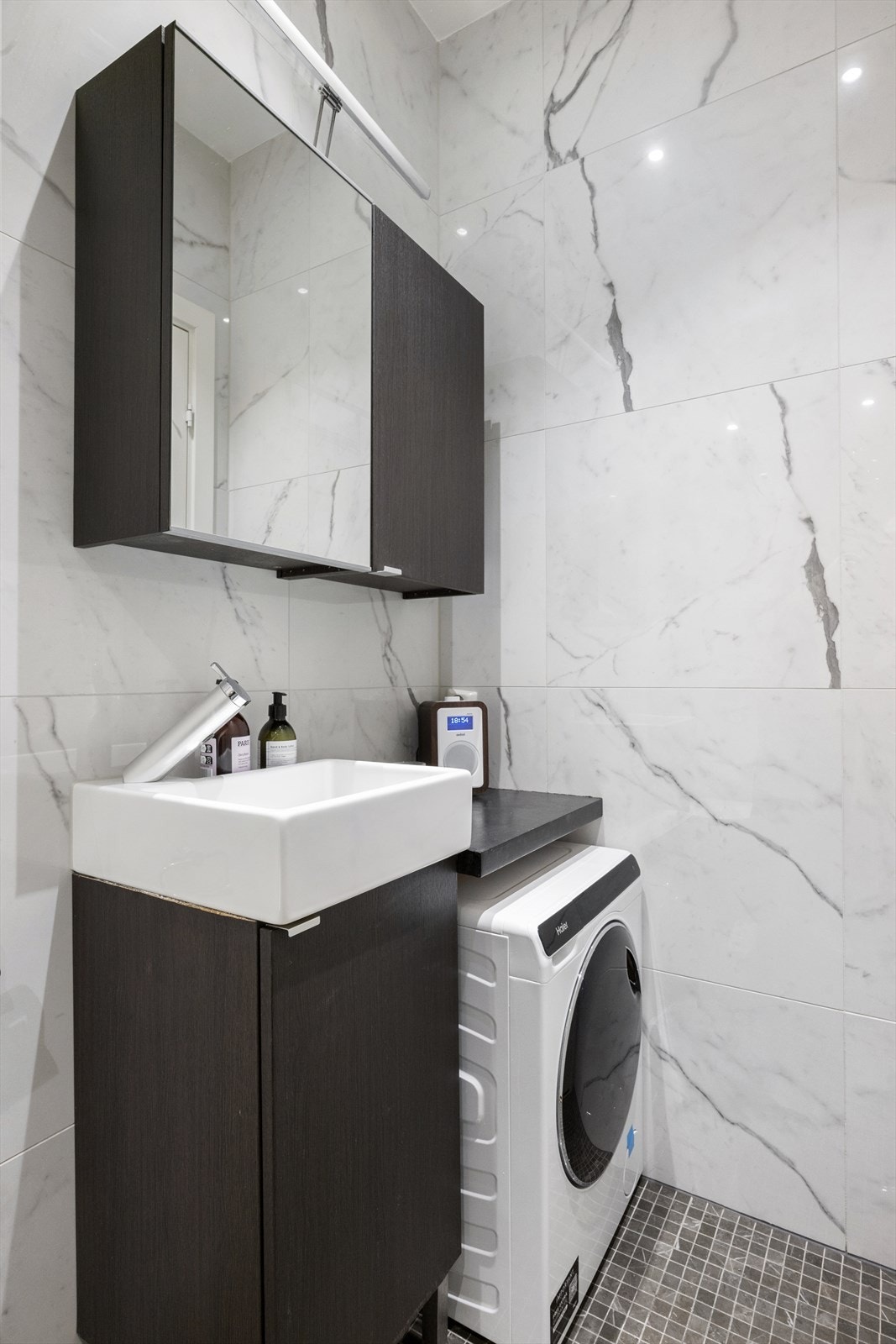 Dusj med innfellbare dører i herdet glass og opplegg for vaskemaskin. Badet har for øvrig oppdriftsventilasjon med ventil på vegg og luftespalte med lufttilførsel under dør. Galleribilde