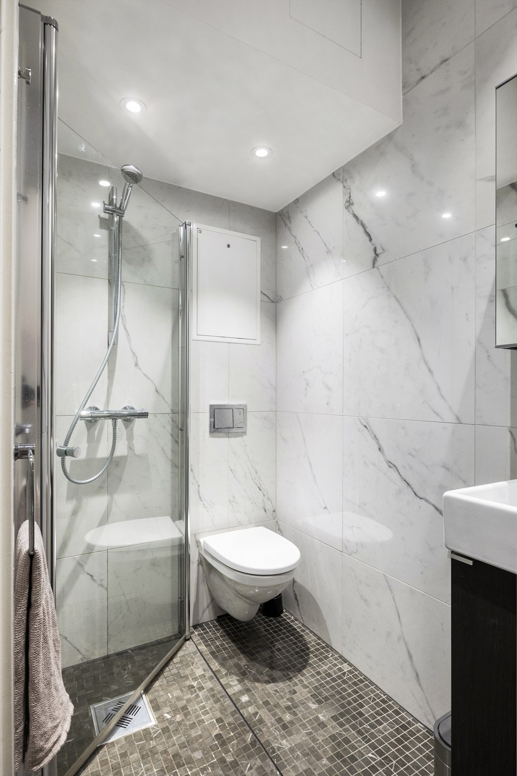 Badet er utstyrt med benkeskap og veggskap(m/ speilfronter) med glatte fronter. Servant med belysning over og veggfestet klosett med innebygget sisterne. Galleribilde