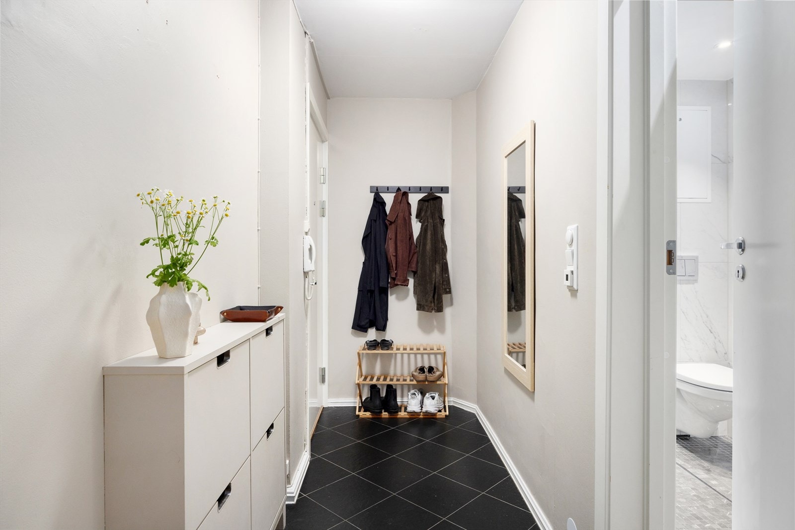 En romslig og delikat entré ønsker deg velkommen inn. Her er det plass til garderobeskap, knagger og skostativ. Galleribilde