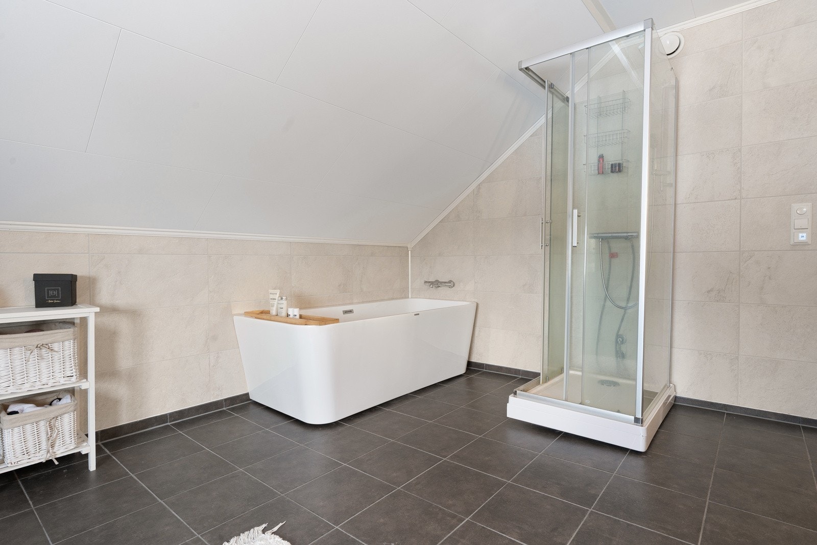 Badet er utstyrt med både badekar og dusjkabinett.