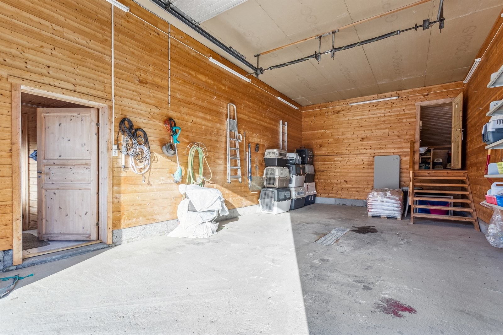 Stor garasje med god takhøyde med trapp opp til en del av katteoppholdet. Galleribilde