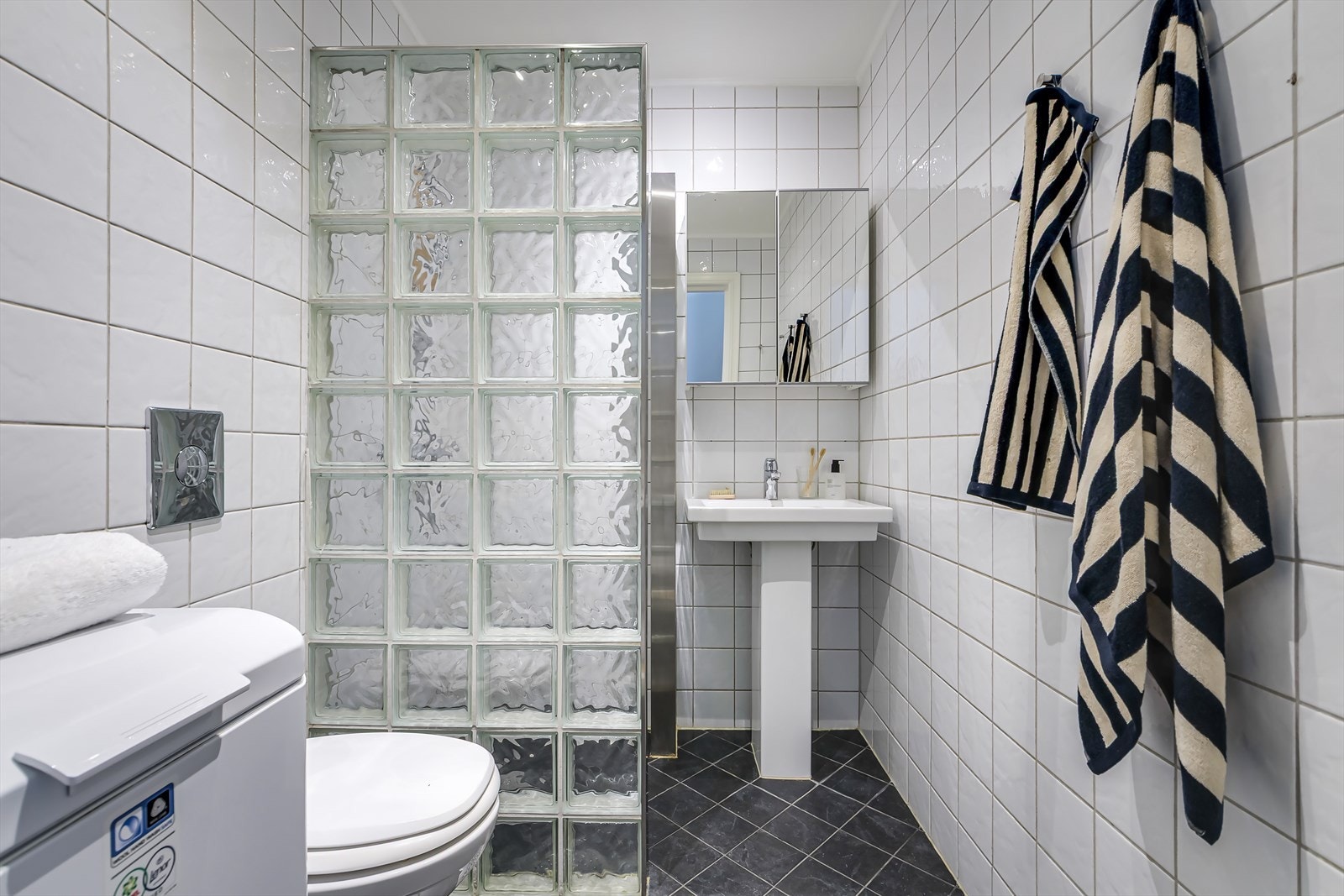 Flislagt bad med gulvvarme, downlights i taket og opplegg for vaskemaskin Galleribilde