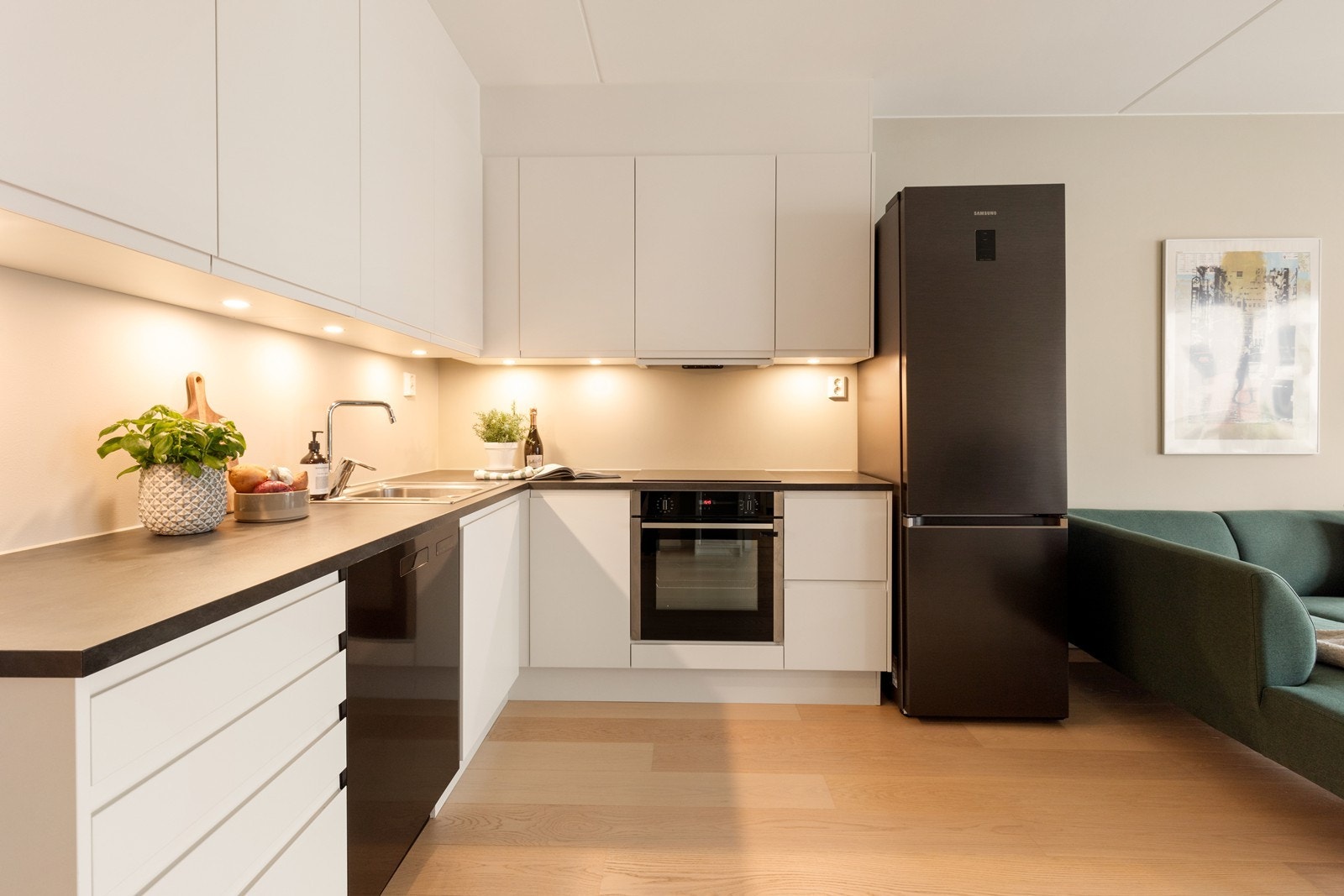 Stilrent Sigdal-kjøkken med integrert stekeovn, induksjonstopp og god belysning ned på benkeplaten. Galleribilde