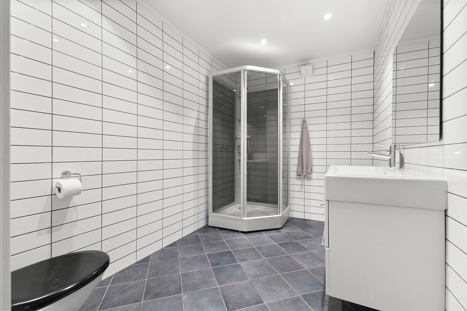 Badet er utstyrt med servantinnredning, dusjkabinett og vegghengt toalett. Avtrekk via balansert ventilasjon. Galleribilde