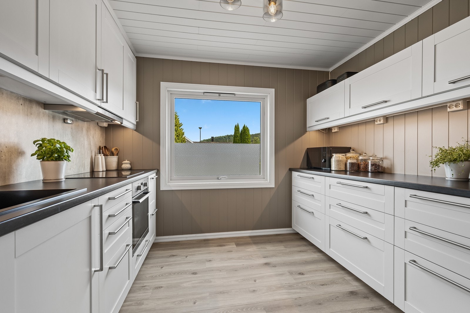 Pent kjøkken fra 2019 med integrerte hvitevarer og godt med oppbevaring og benkeplass Galleribilde