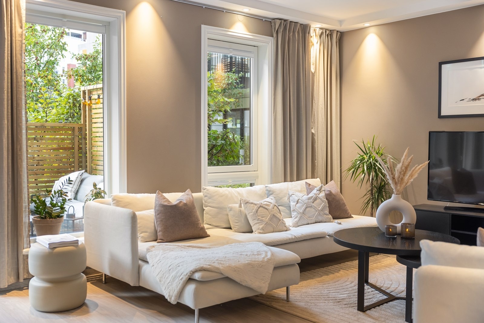 Store vindusflater gir rommet rikelig med naturlig lys, mens de grønne trærne og leveggene utenfor skjermer for innsyn og gir en privat følelse. Galleribilde